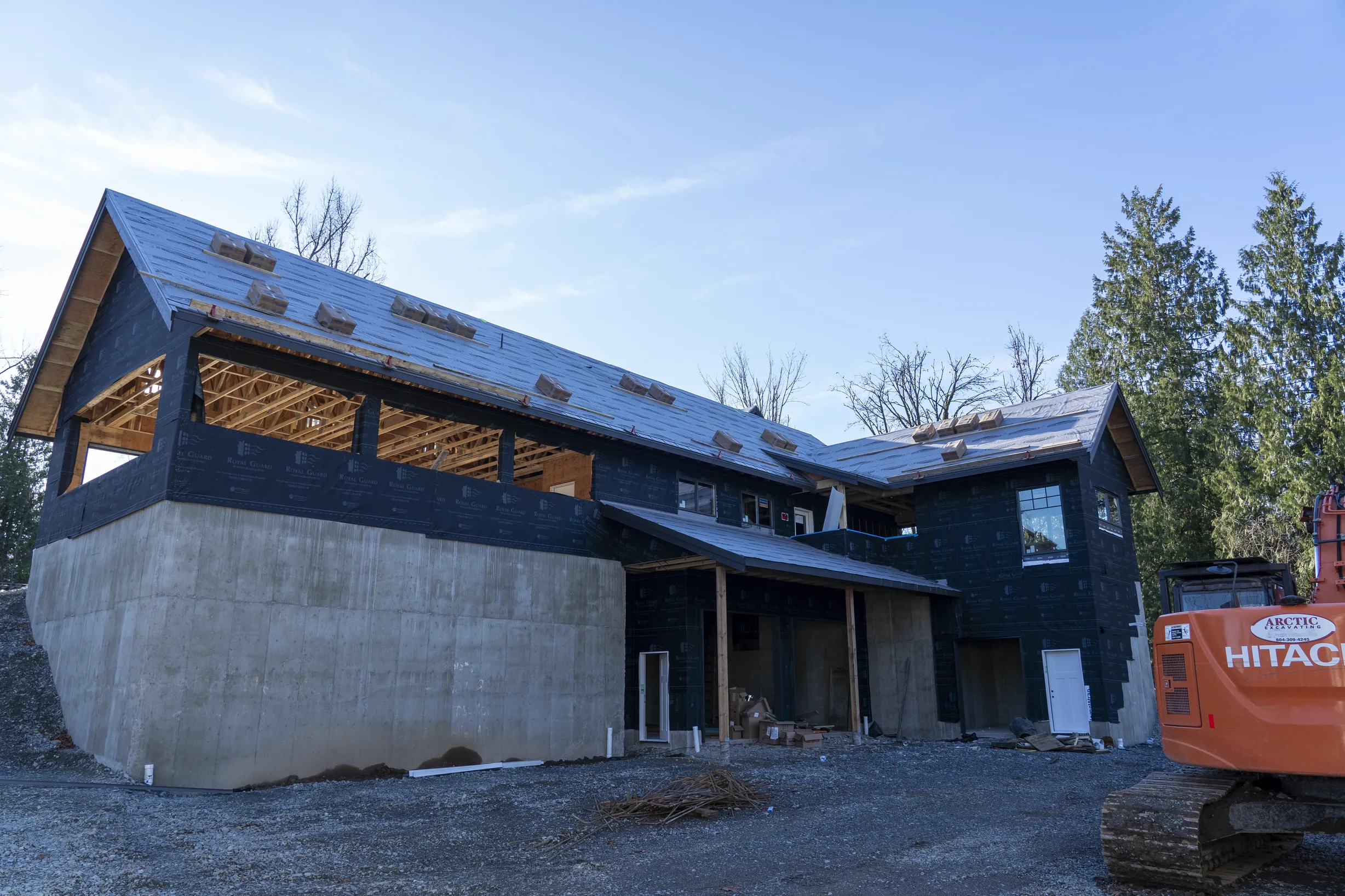 Musket Grey Interlock Slate aluminum roof being installed on a Musket Grey metal roof on a two-storey home among tall, Abbotsford, British Columbia