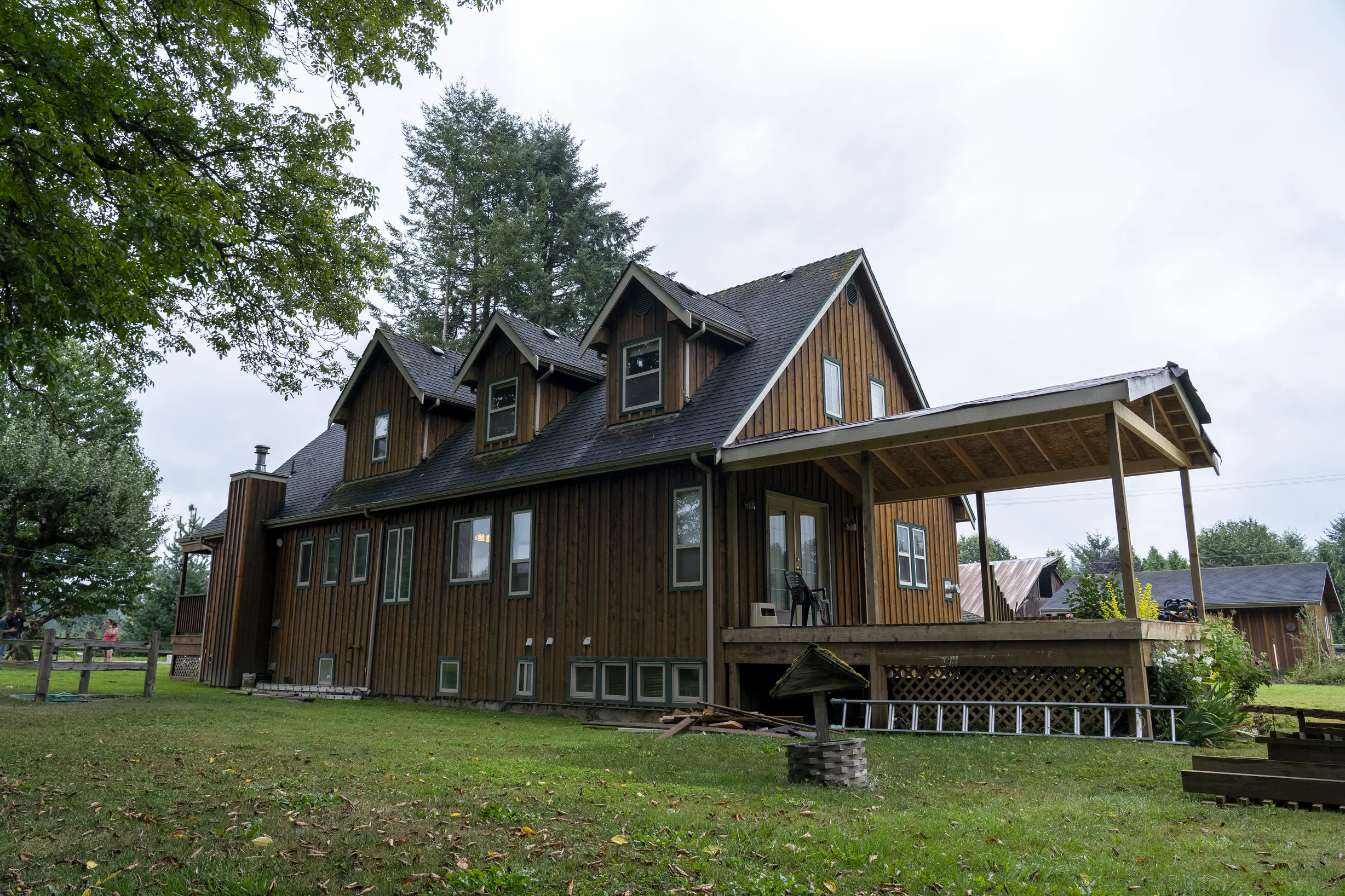 Hunter Green Interlock Slate aluminum roof on a brown two-storey home with dormers among tall trees, Langley, British Columbia