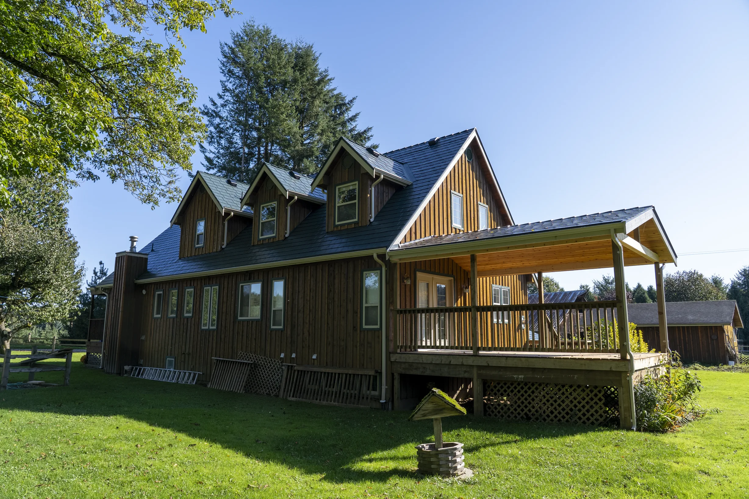 Hunter Green Interlock Slate aluminum roof on a brown single-storey home with a covered porch in a forest, Langley, British Columbia