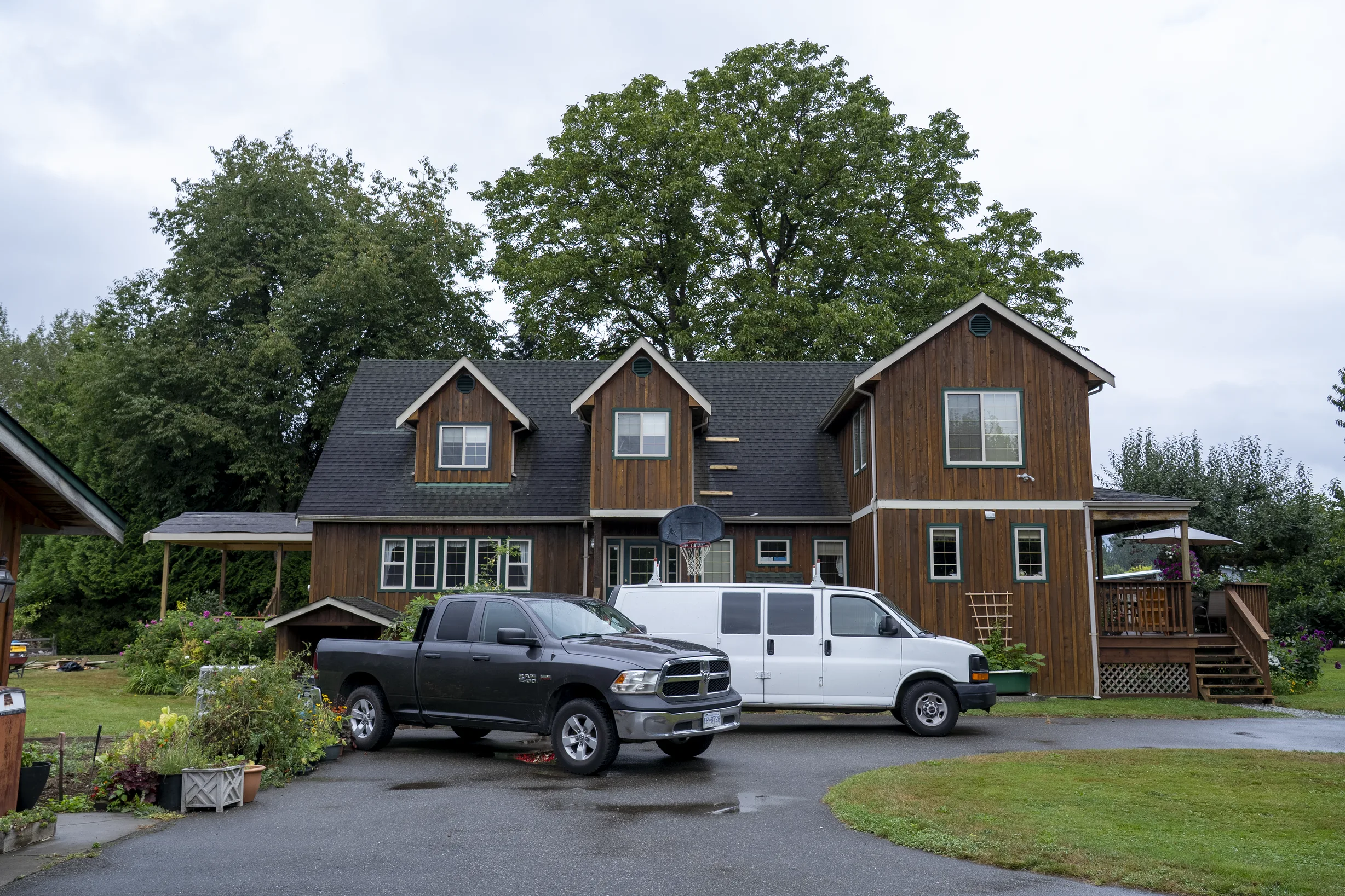 Hunter Green Interlock Slate aluminum roof on a brown two-storey home with dormers among tall pines, Langley, British Columbia