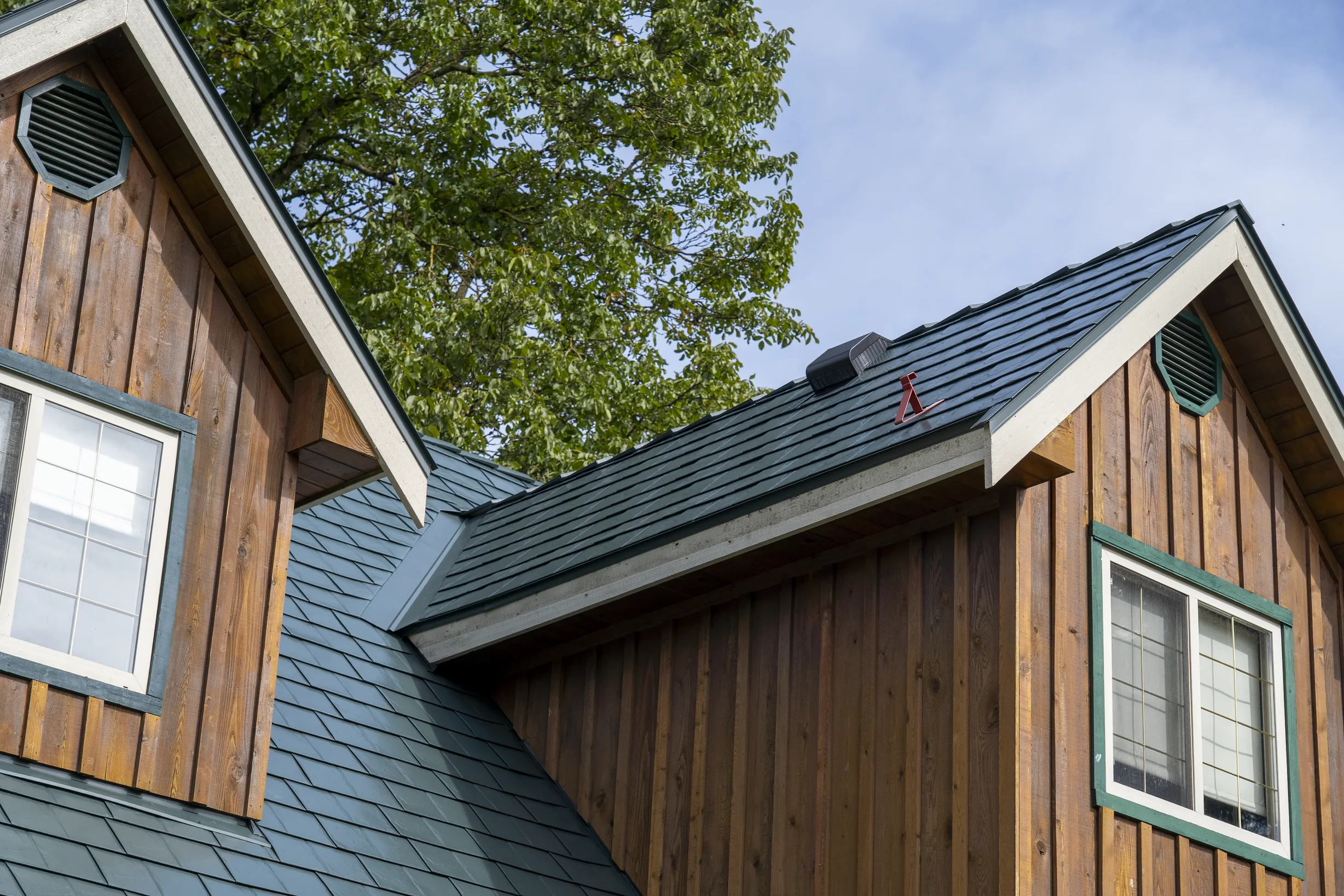 Hunter Green Interlock Slate aluminum roof on a brown house with a green roof among tall trees, Langley, British Columbia