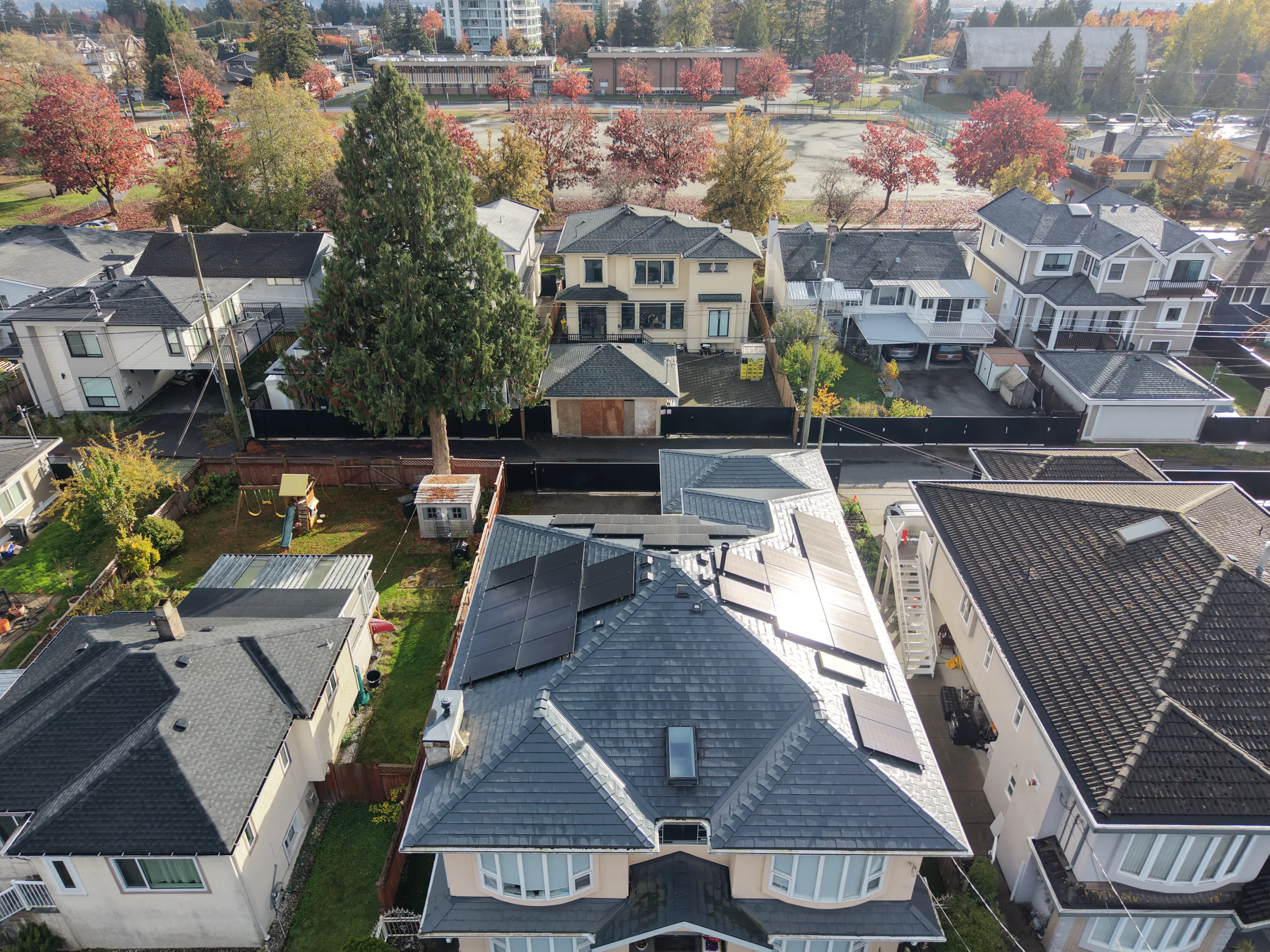 Deep Charcoal Interlock Slate aluminum roof on a two-storey home with dormers among tall trees in a, Burnaby, British Columbia
