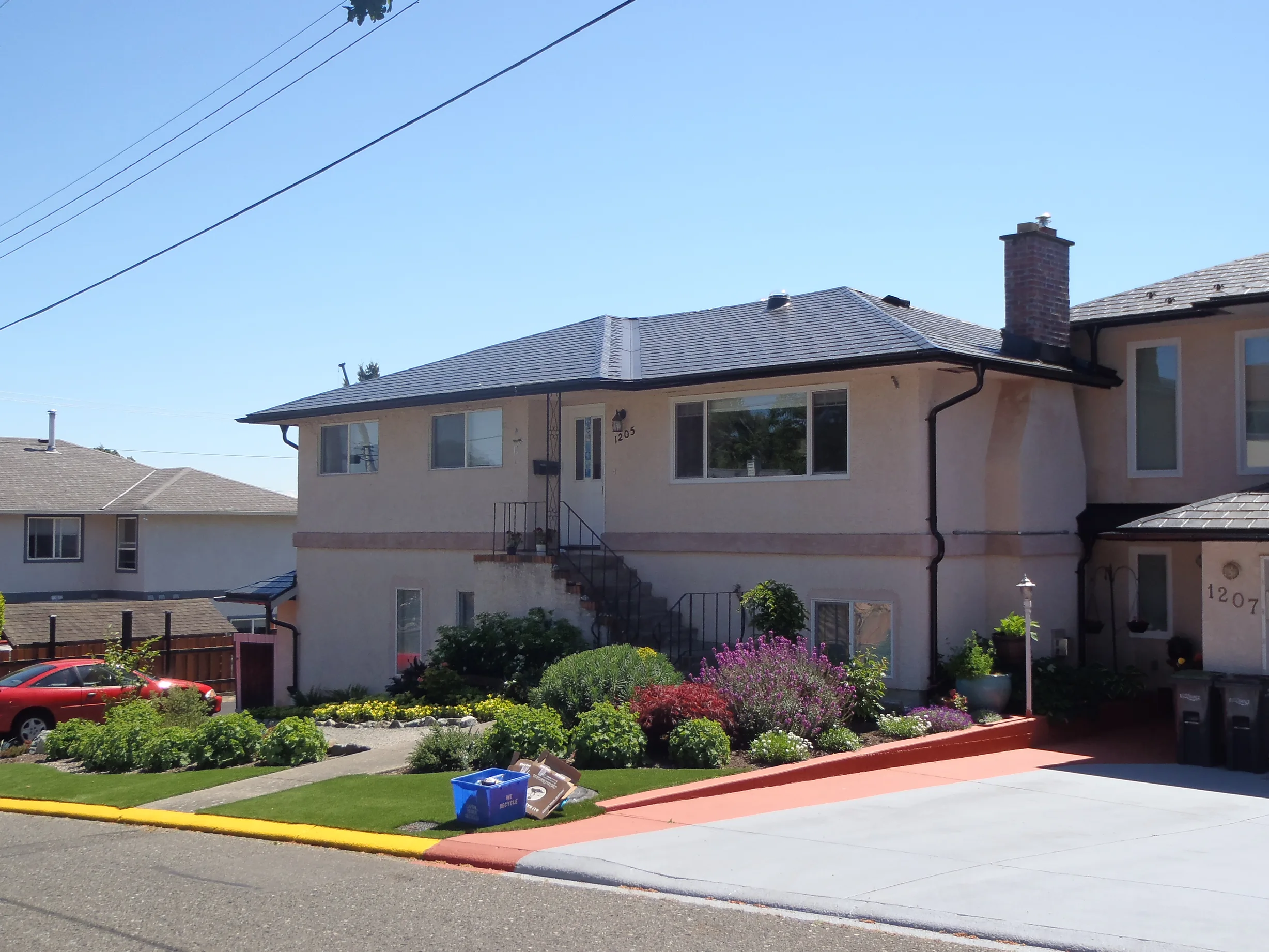 Black Interlock Slate aluminum roof on a beige two-storey home with a metal roof and chimney in a, Victoria, British Columbia