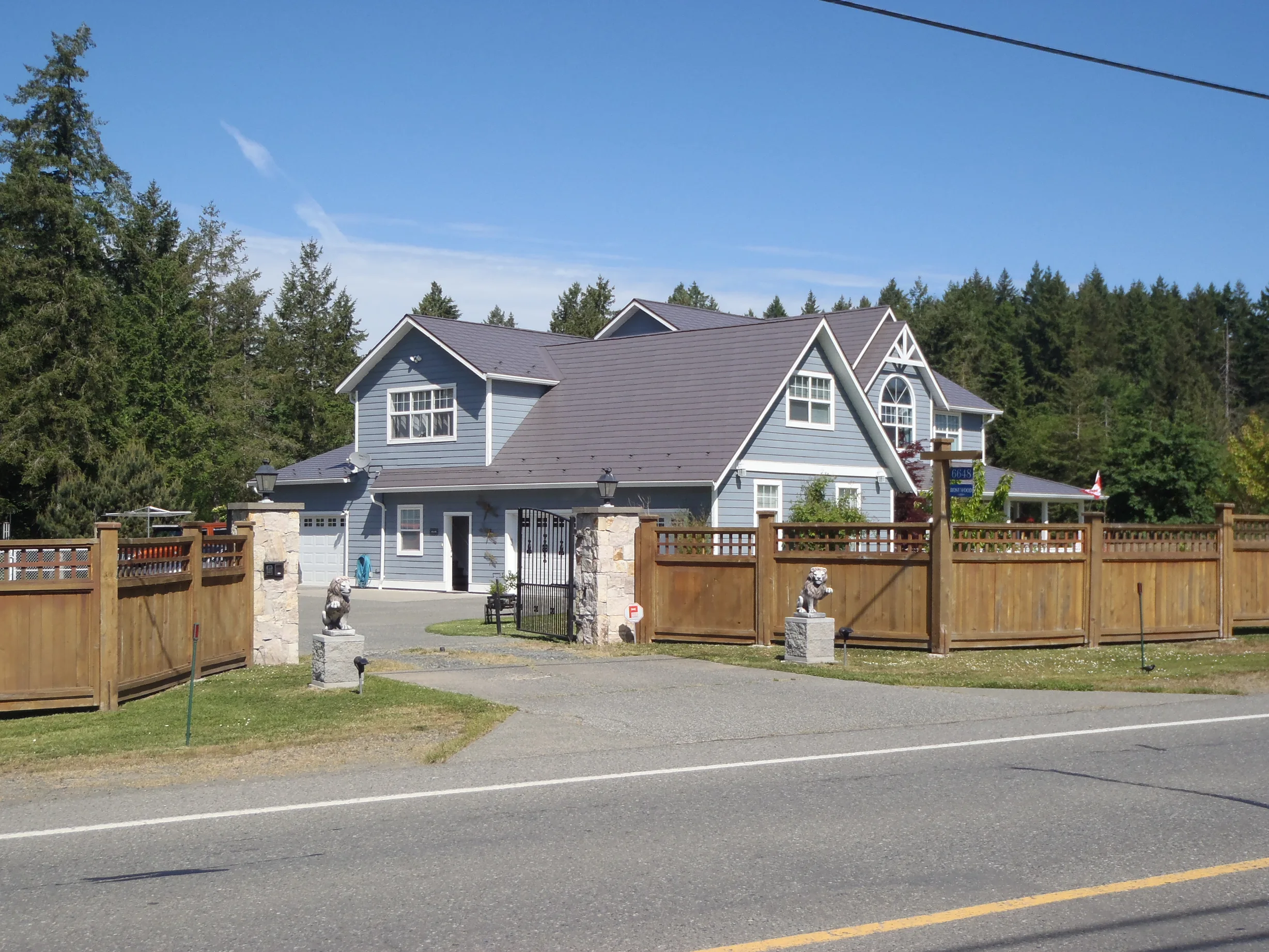 Weathered Interlock Slate aluminum roof on a grey modern home with dormers among tall evergreens, Duncan, British Columbia