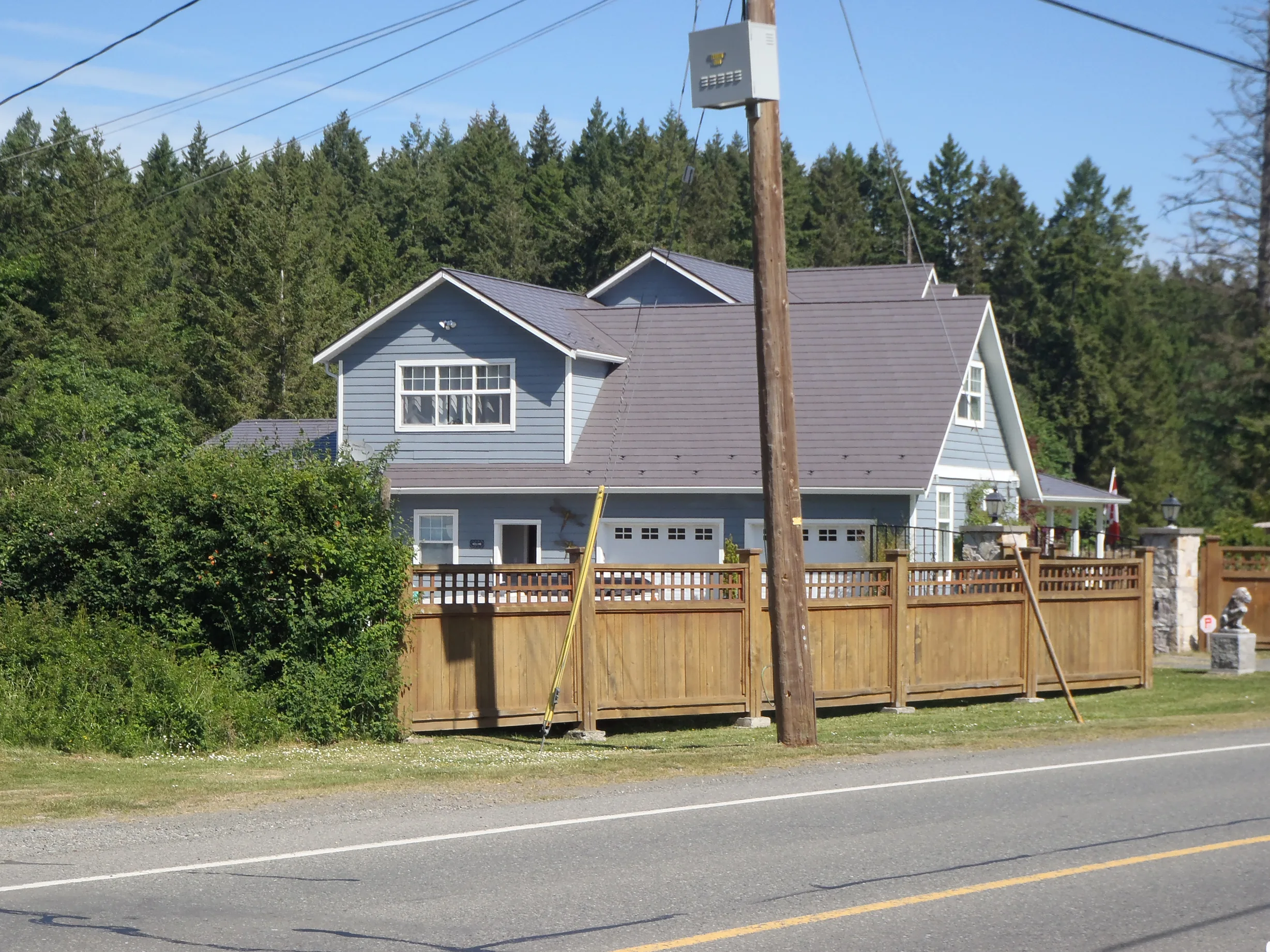 Weathered Interlock Slate aluminum roof on a two-storey home with a grey metal roof in a forested area, Duncan, British Columbia