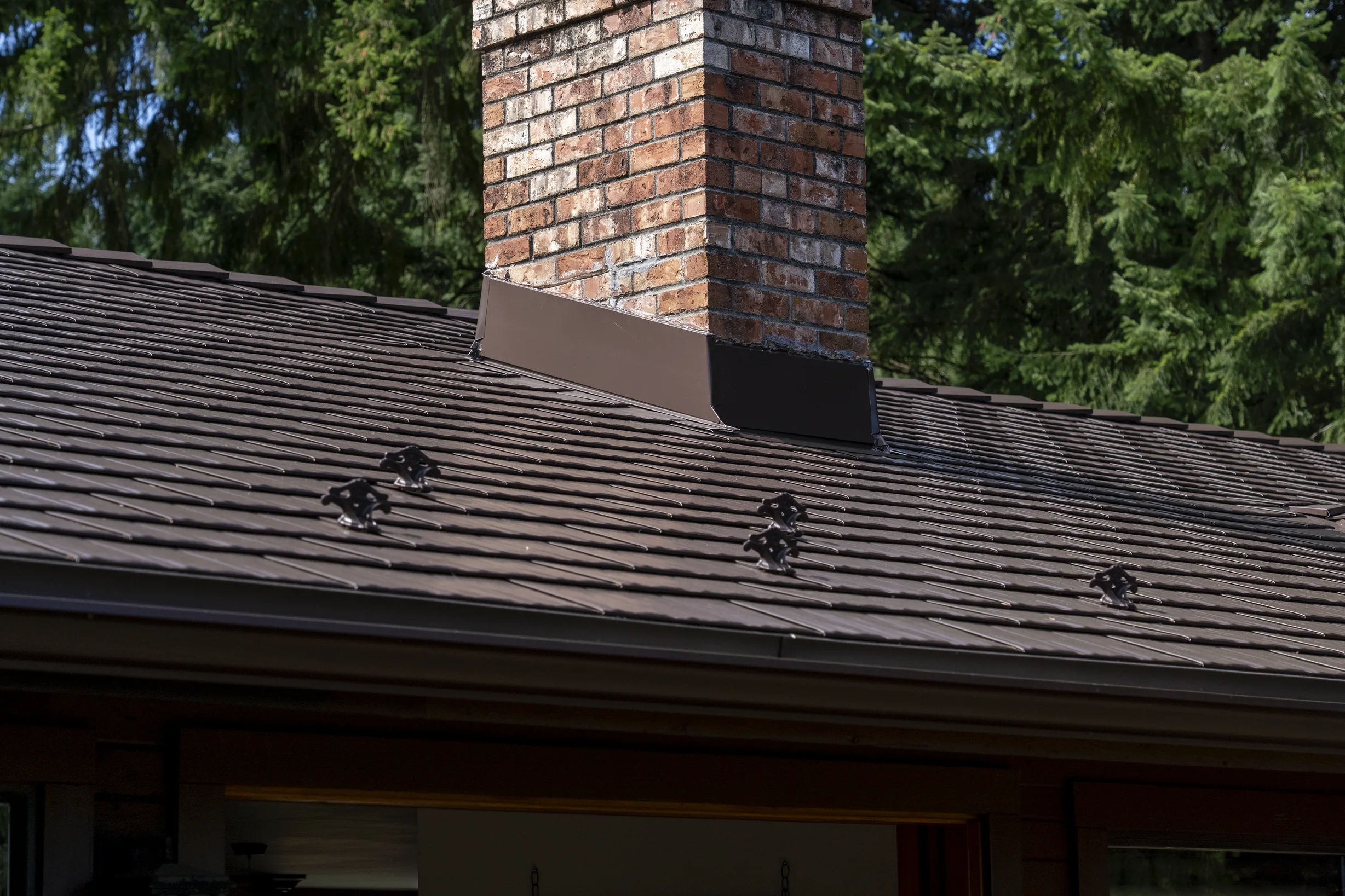 Colonial Brown Interlock Cedar Shingle aluminum roof on a brown colonial home with dormers among tall pines, Salt Spring Island, British Columbia