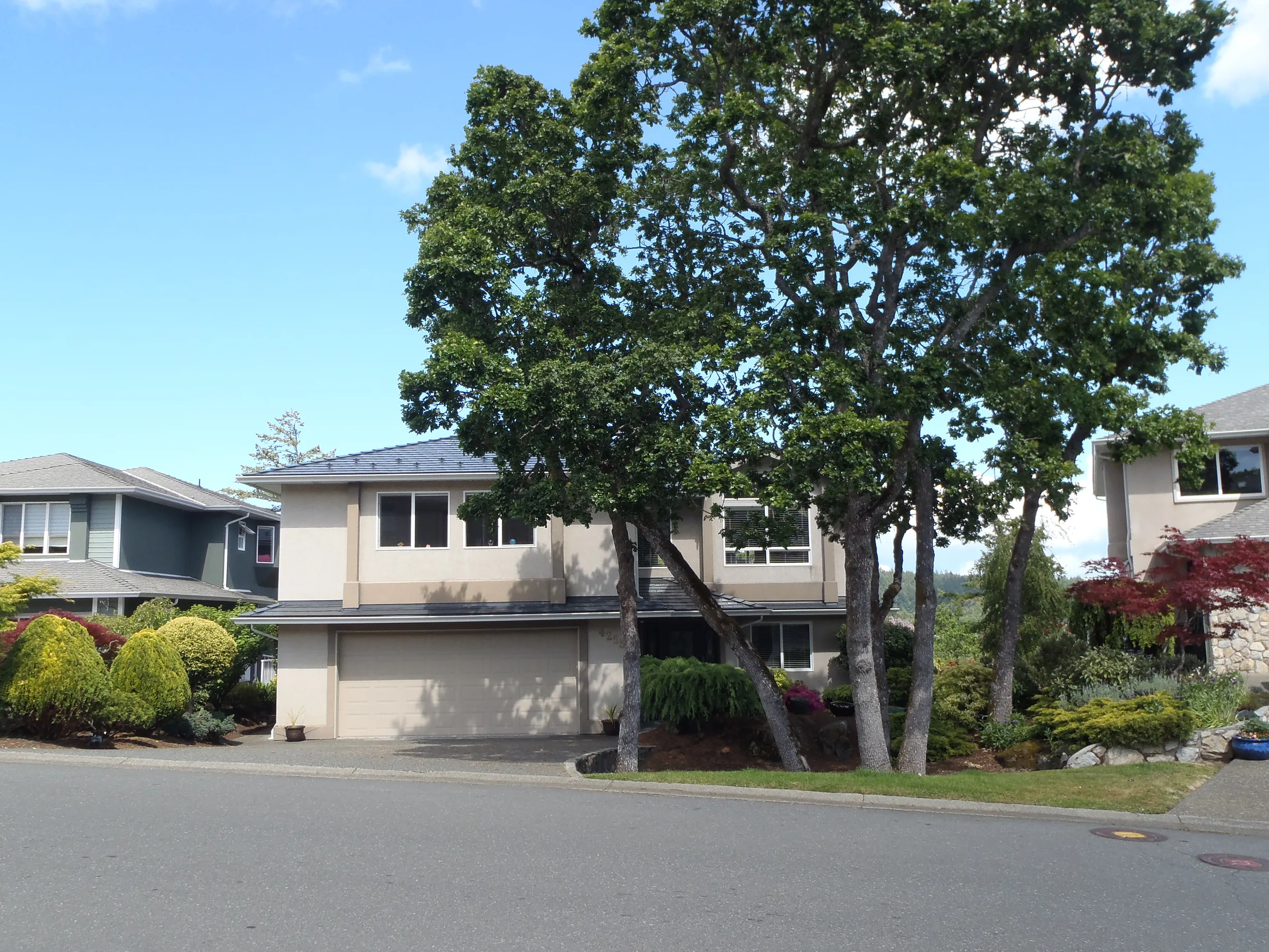 Deep Charcoal Interlock Slate aluminum roof on a two-storey beige home with dormers in a suburban, Victoria, British Columbia