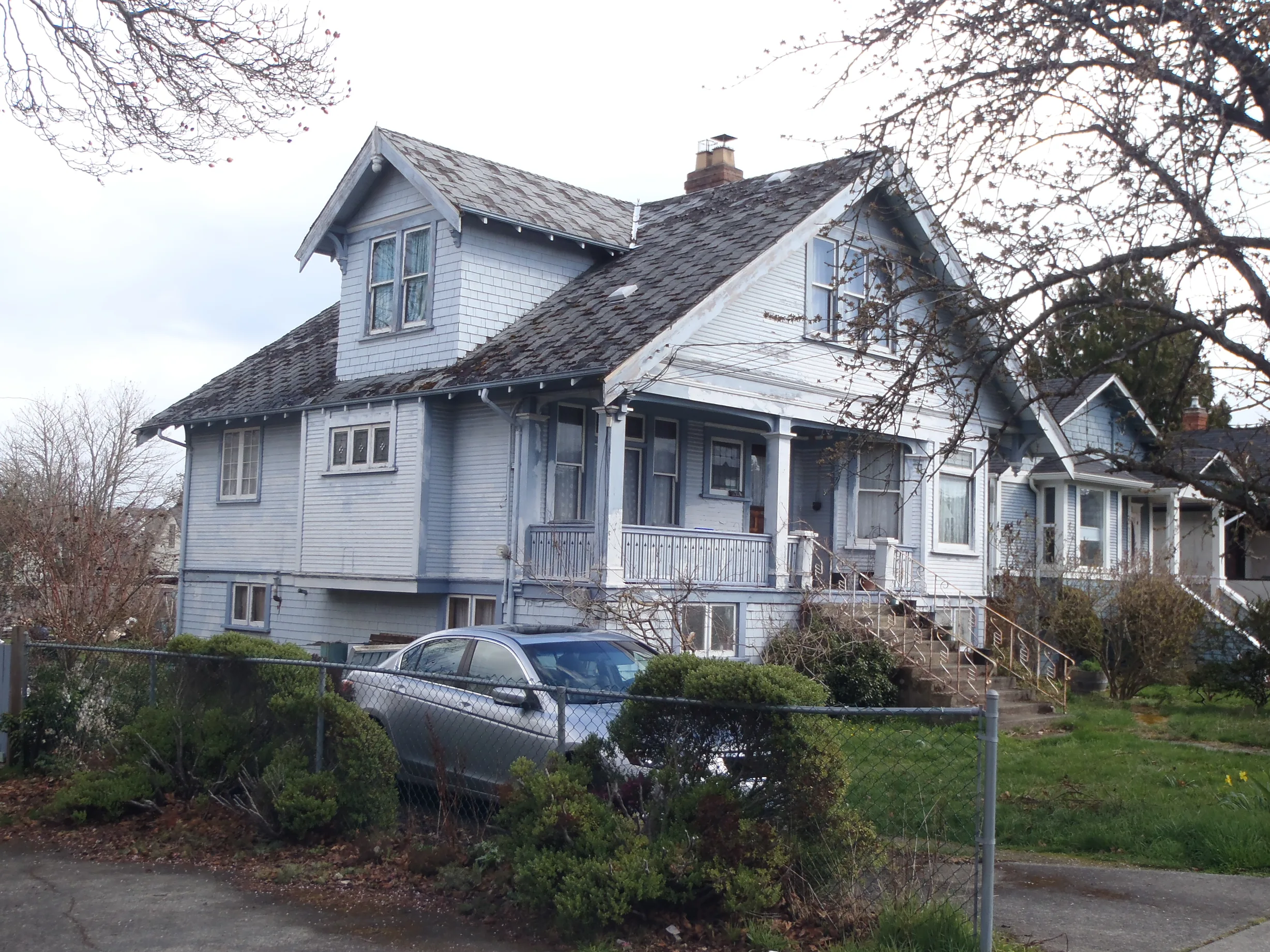 Tudor Brown Interlock Cedar Shingle aluminum roof on a light grey two-storey Tudor home with dormers and a metal, Victoria, British Columbia