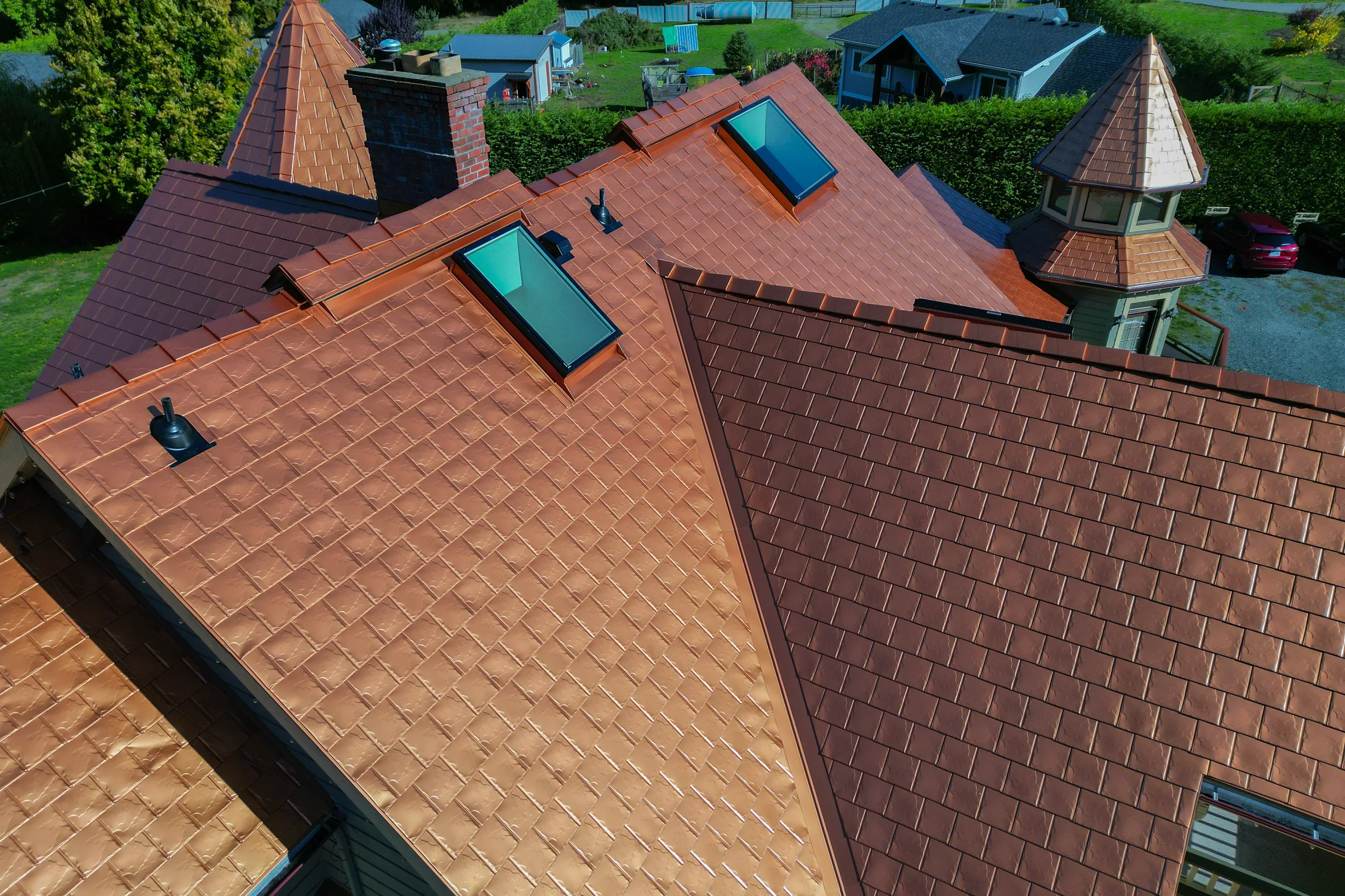 Copper Penny Interlock Slate aluminum roof on a red house with a copper penny metal roof in a suburban, Ladysmith, British Columbia