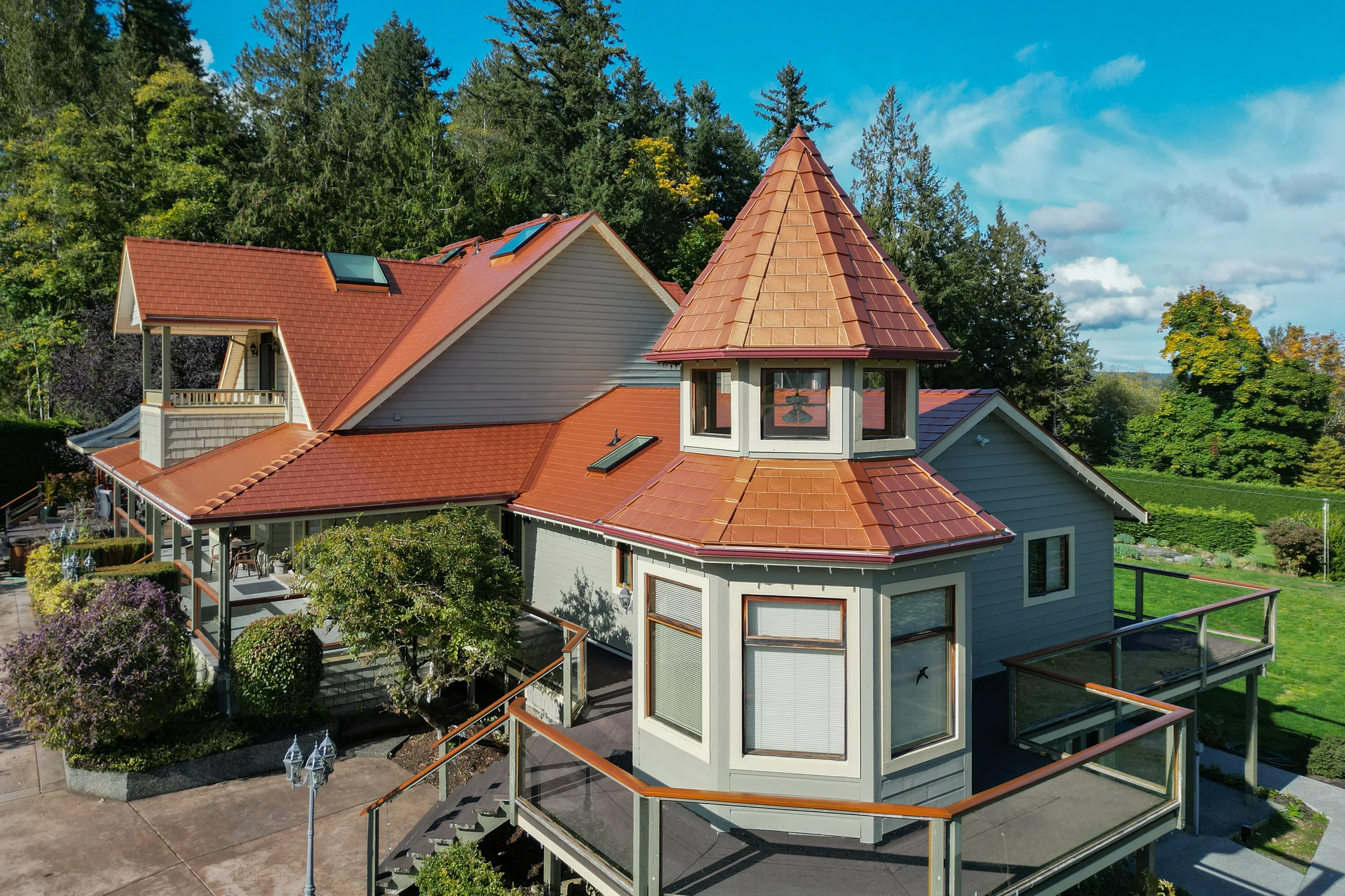 Copper Penny Interlock Slate aluminum roof on a grey single-family Craftsman home with dormers among tall, Ladysmith, British Columbia