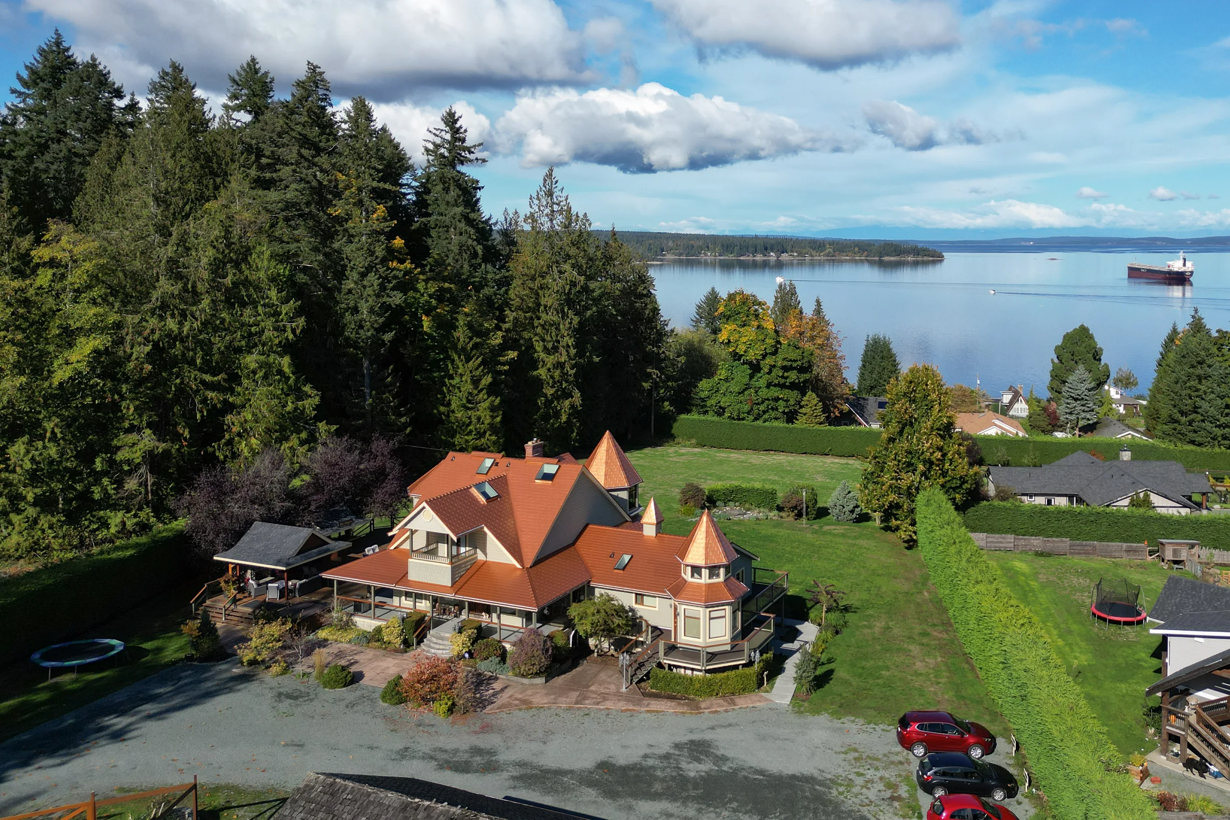 Copper Penny Interlock Slate aluminum roof on a cream house with a copper penny metal roof on a lake shore, Ladysmith, British Columbia