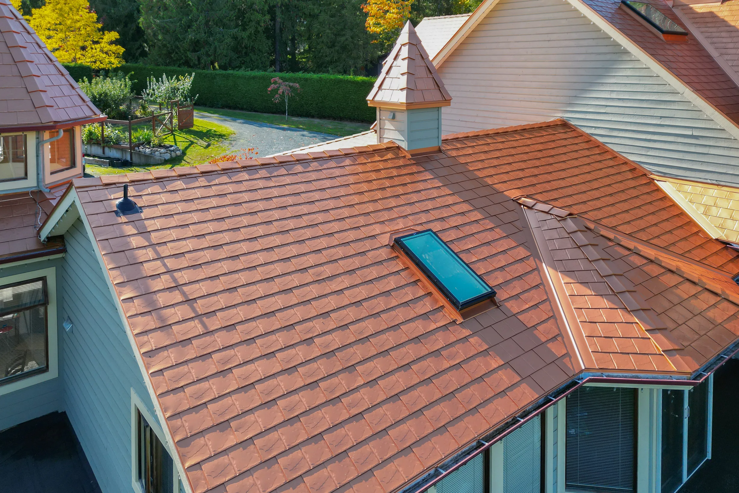 Copper Penny Interlock Slate aluminum roof on a two-storey home with copper penny metal roof in a lush, Ladysmith, British Columbia
