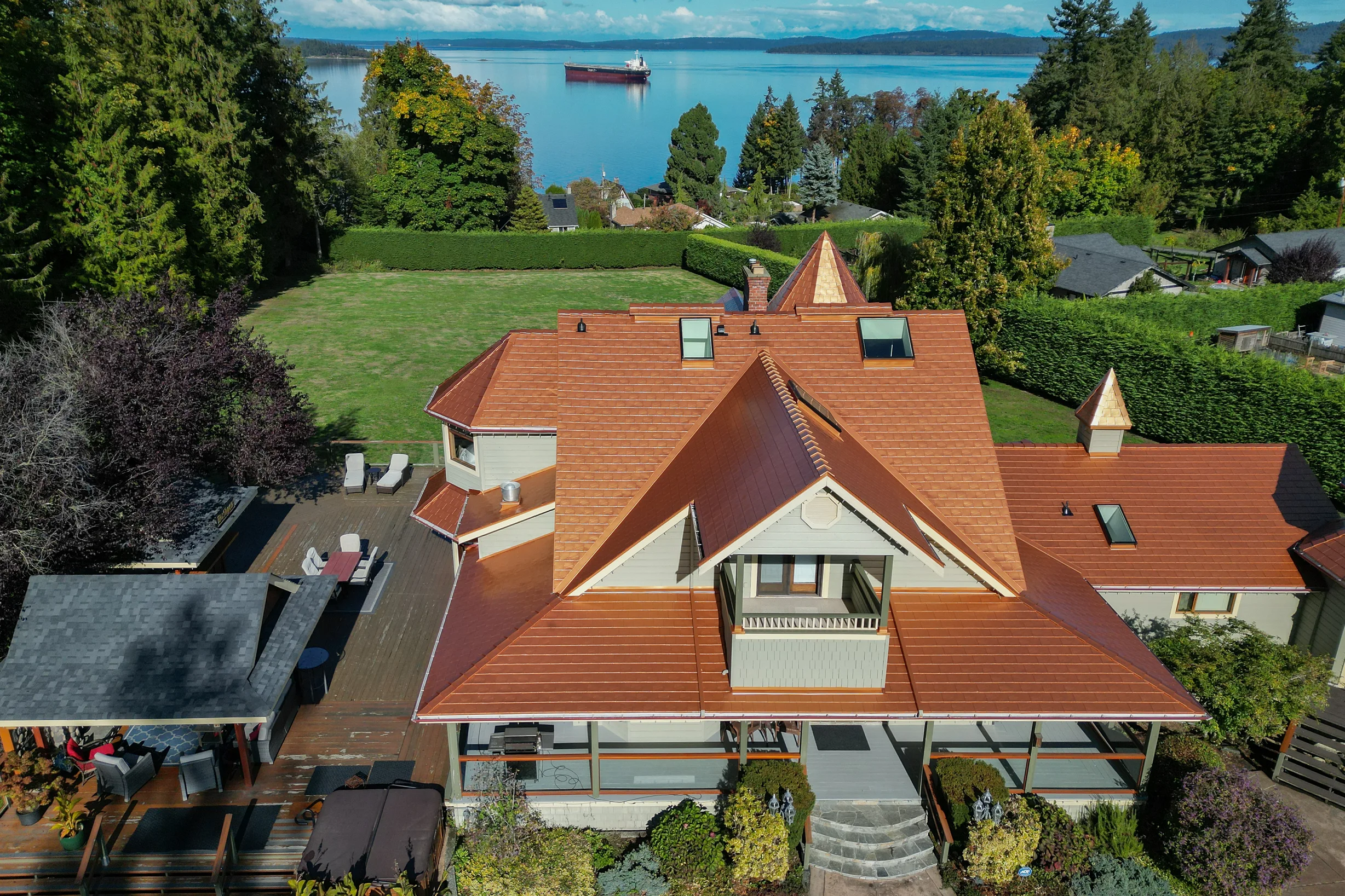Copper Penny Interlock Slate aluminum roof on a white home with a copper penny metal roof among tall, Ladysmith, British Columbia