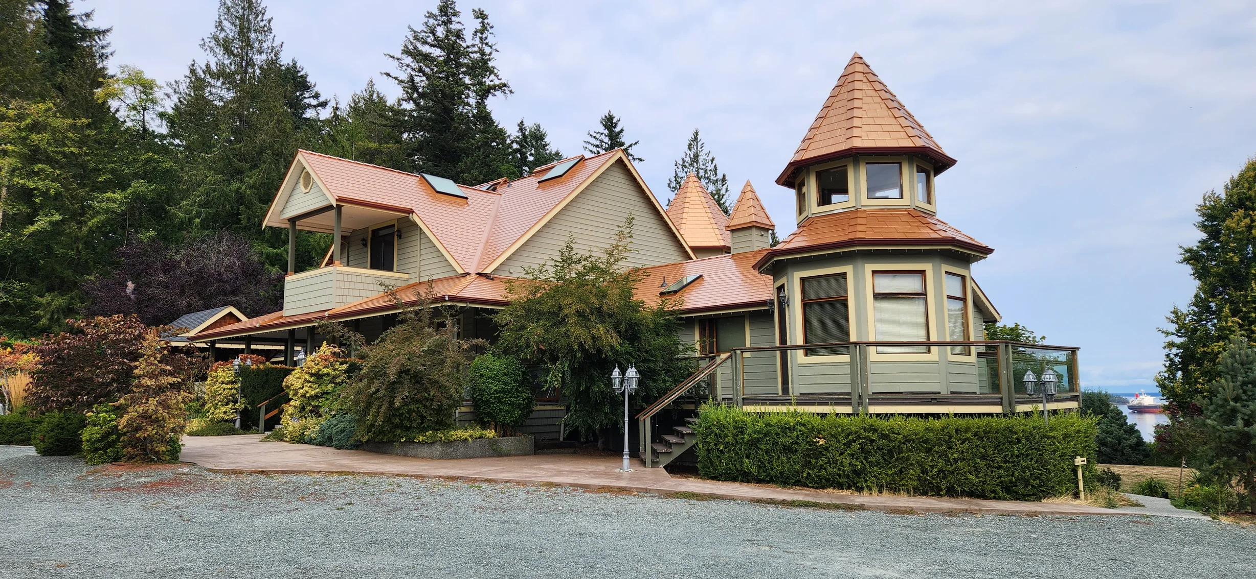 Copper Penny Interlock Slate aluminum roof on a beige single-family home with a metal roof in a forested, Ladysmith, British Columbia