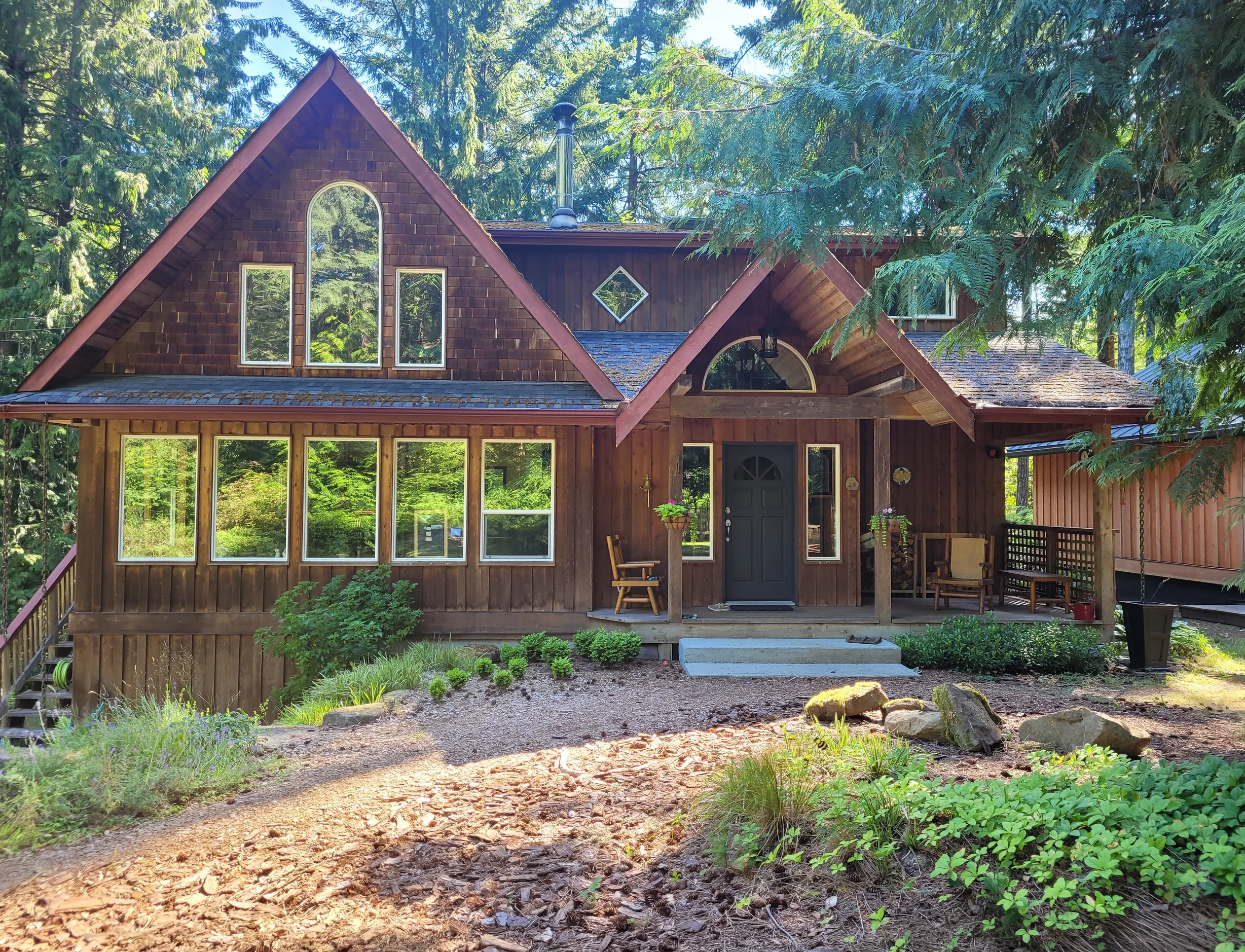 Deep Charcoal Interlock Slate aluminum roof on a brown A-frame home with a gable roof among tall trees, Gabriola Island, British Columbia