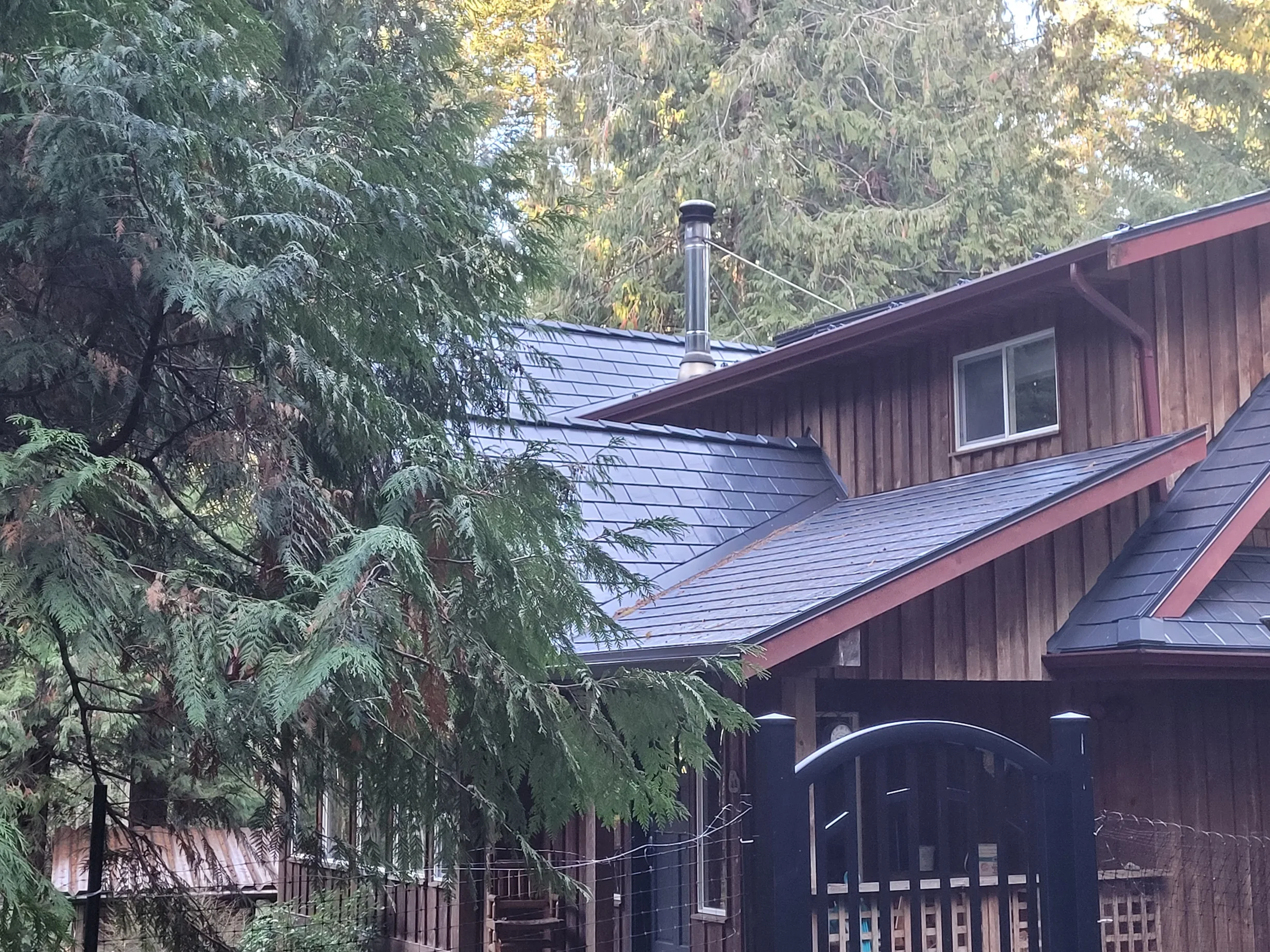 Deep Charcoal Interlock Slate aluminum roof on a brown single-storey cottage with a metal roof and dormer, Gabriola Island, British Columbia