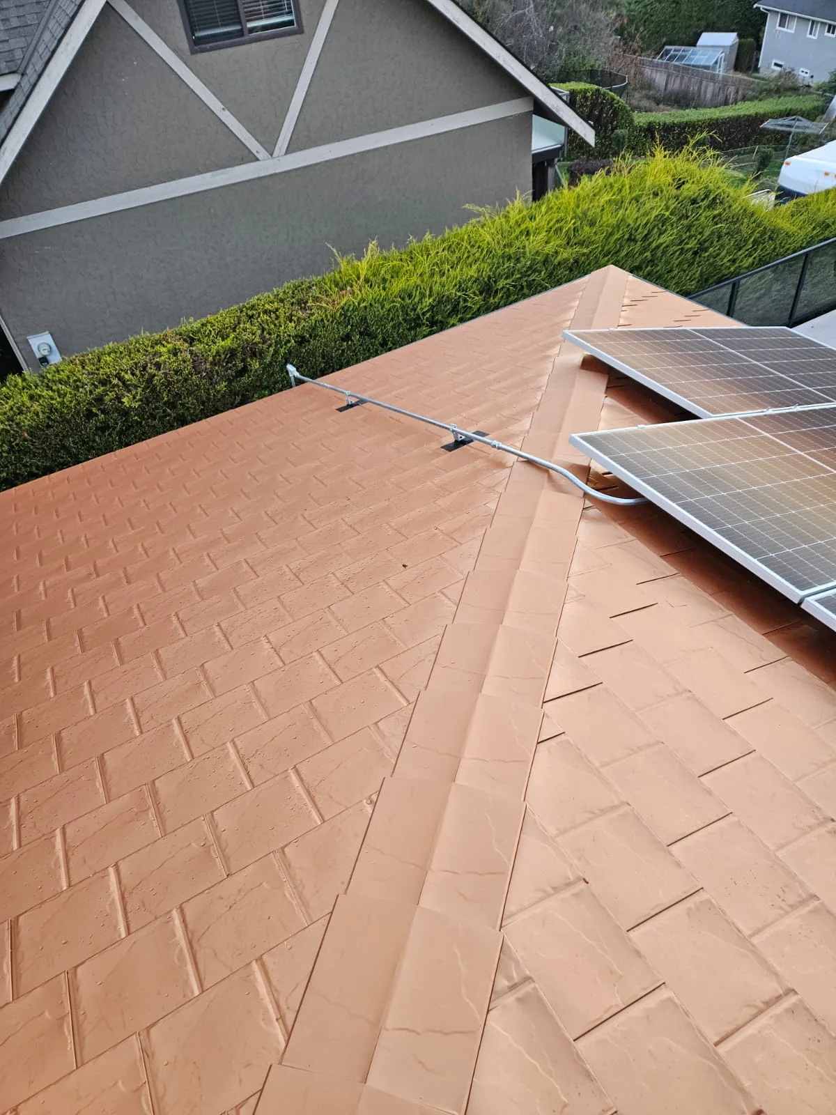 Copper Penny Interlock Slate aluminum roof on a single-family home with a gray exterior and white trim, Victoria, British Columbia