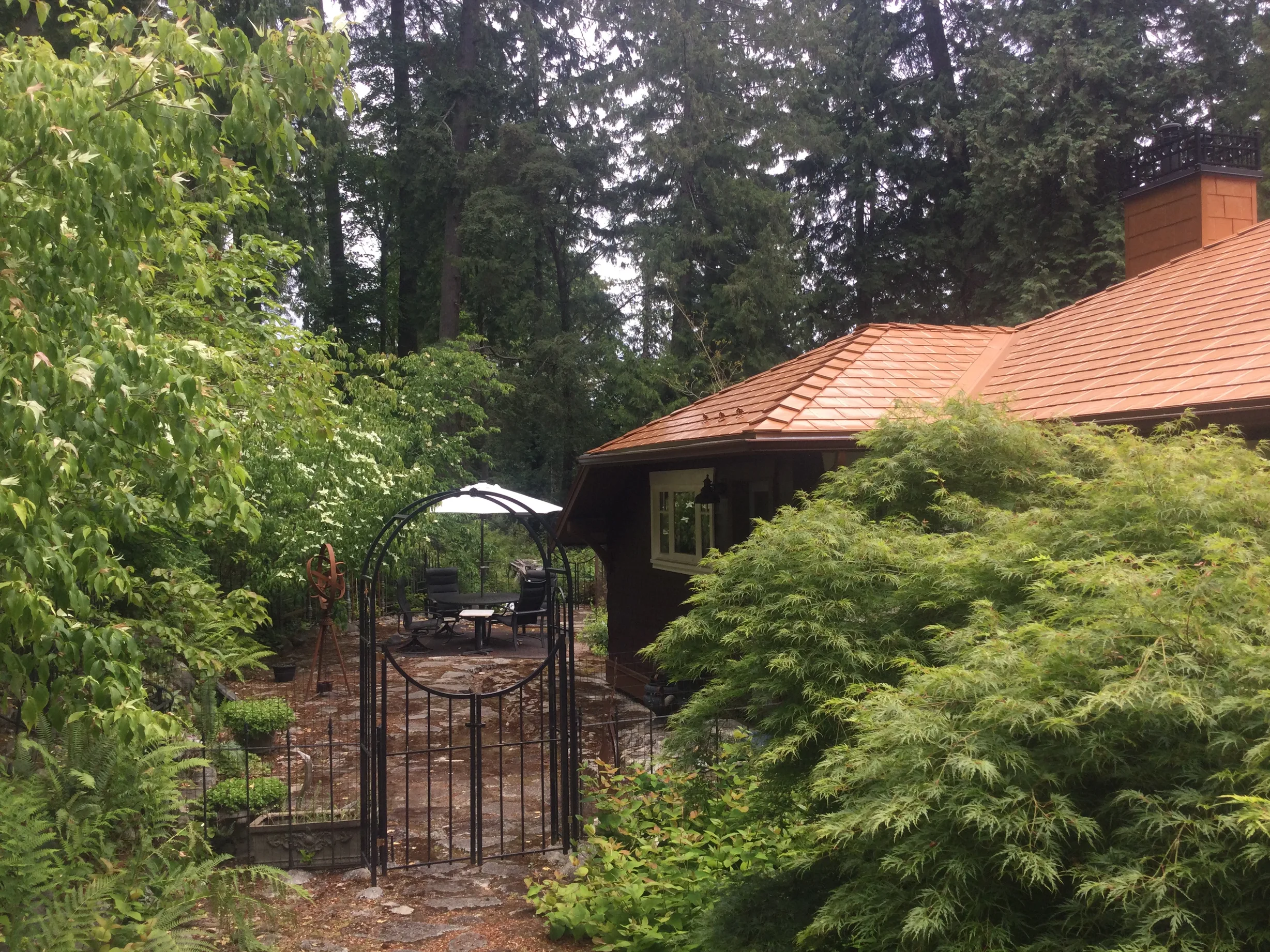 Copper Penny Interlock Slate aluminum roof on a brown home with a copper penny metal roof among tall, Cowichan Bay, British Columbia