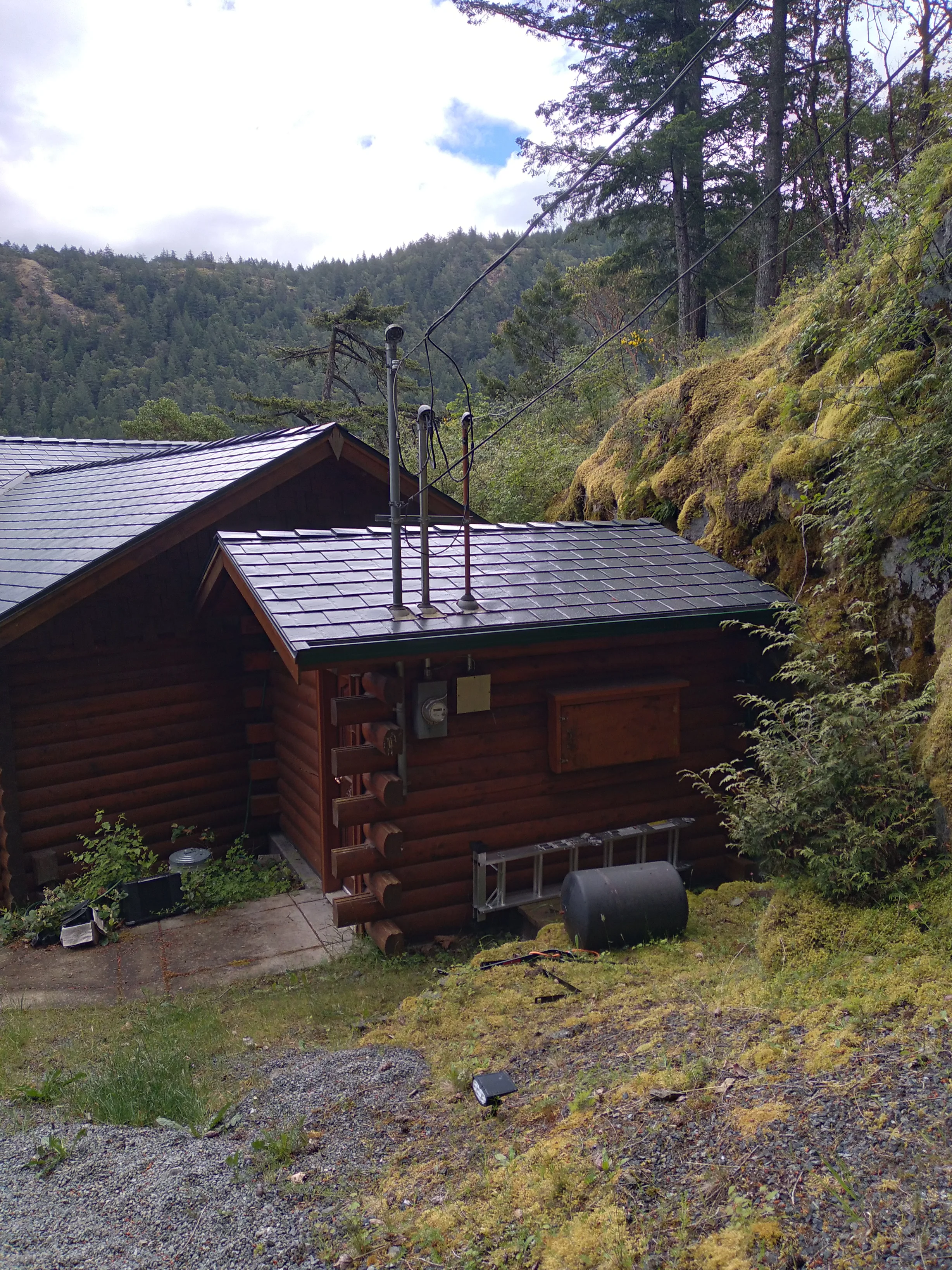 Deep Charcoal Interlock Slate aluminum roof on a log cabin with a metal roof in a forested mountain setting, Juan de Fuca, British Columbia