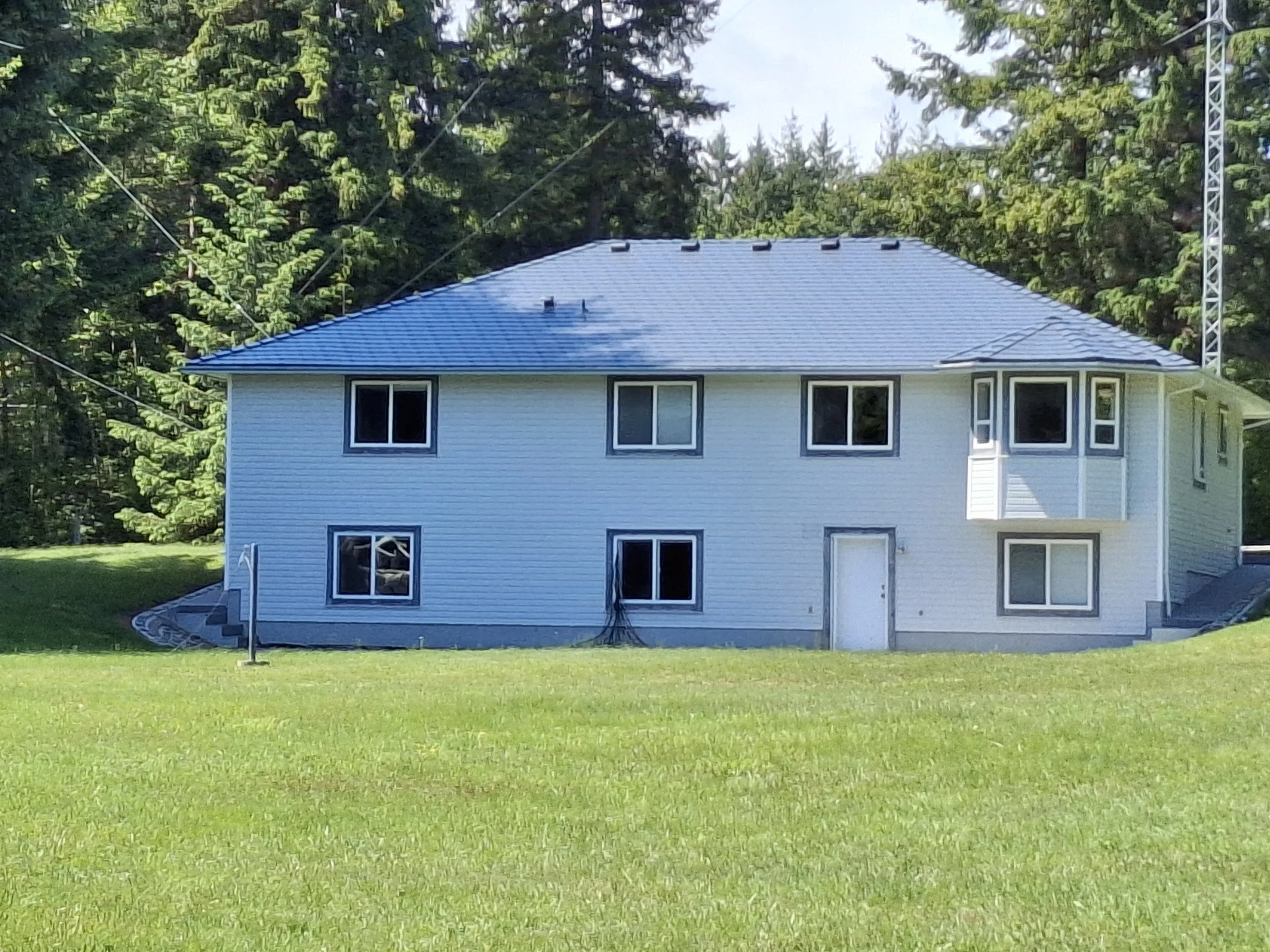 Deep Charcoal Interlock Slate aluminum roof on a white modern home with a metal roof in a forested rural, Courtenay, British Columbia