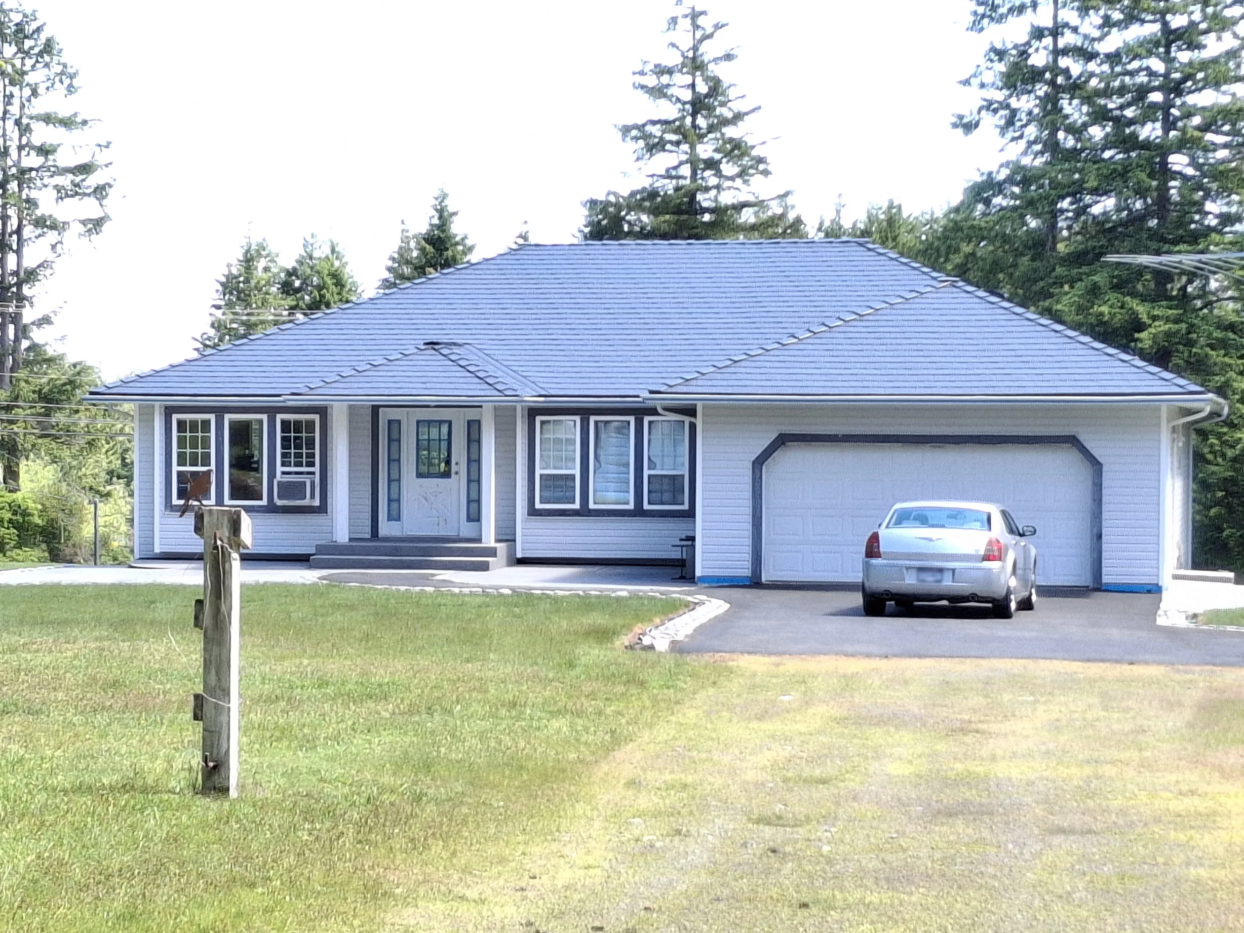 Deep Charcoal Interlock Slate aluminum roof on a light-colored home with a metal roof in a coastal forest, Courtenay, British Columbia