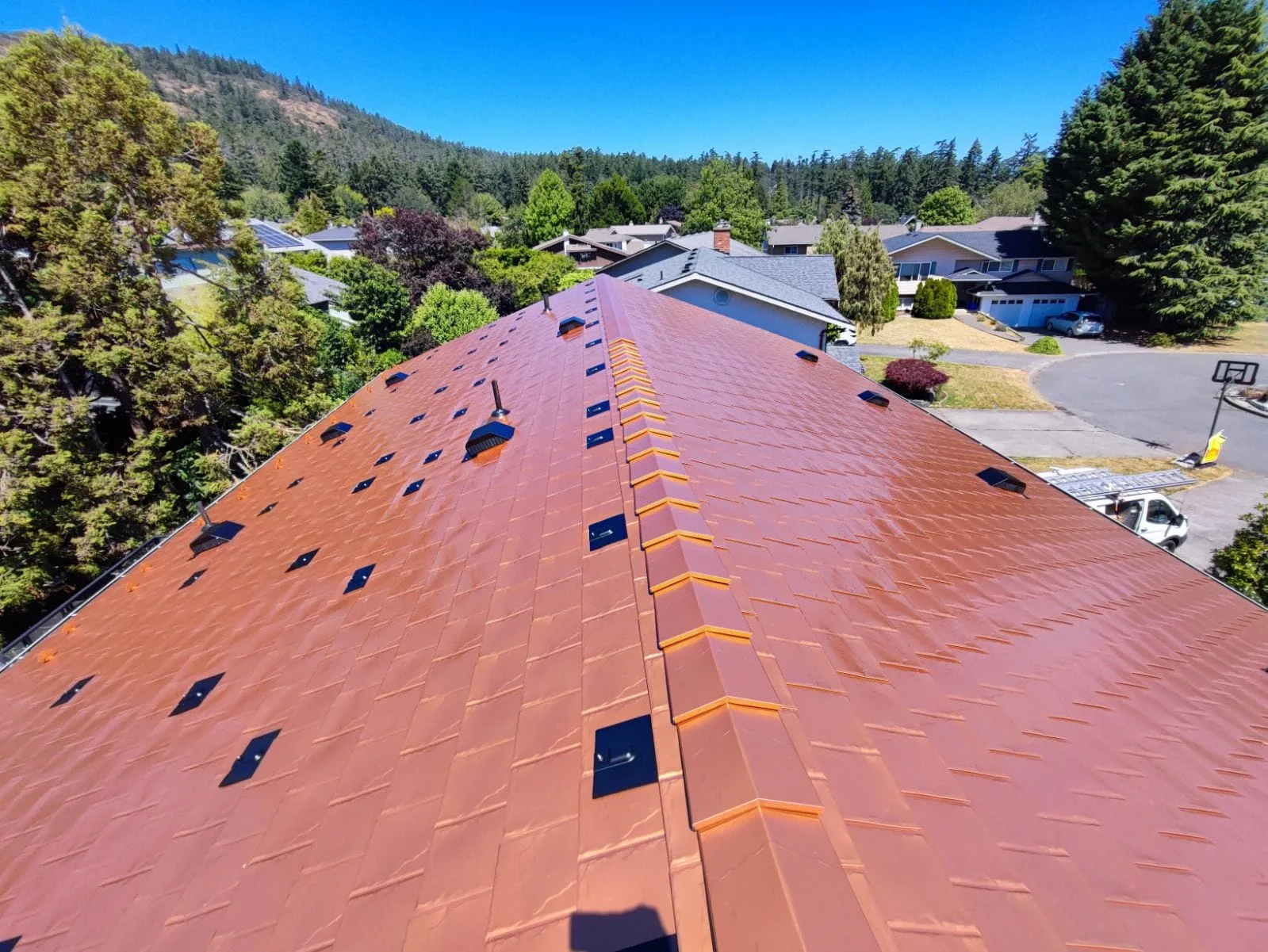Copper Penny Interlock Slate aluminum roof on a two-storey home with dormers in a forested area, Victoria, British Columbia
