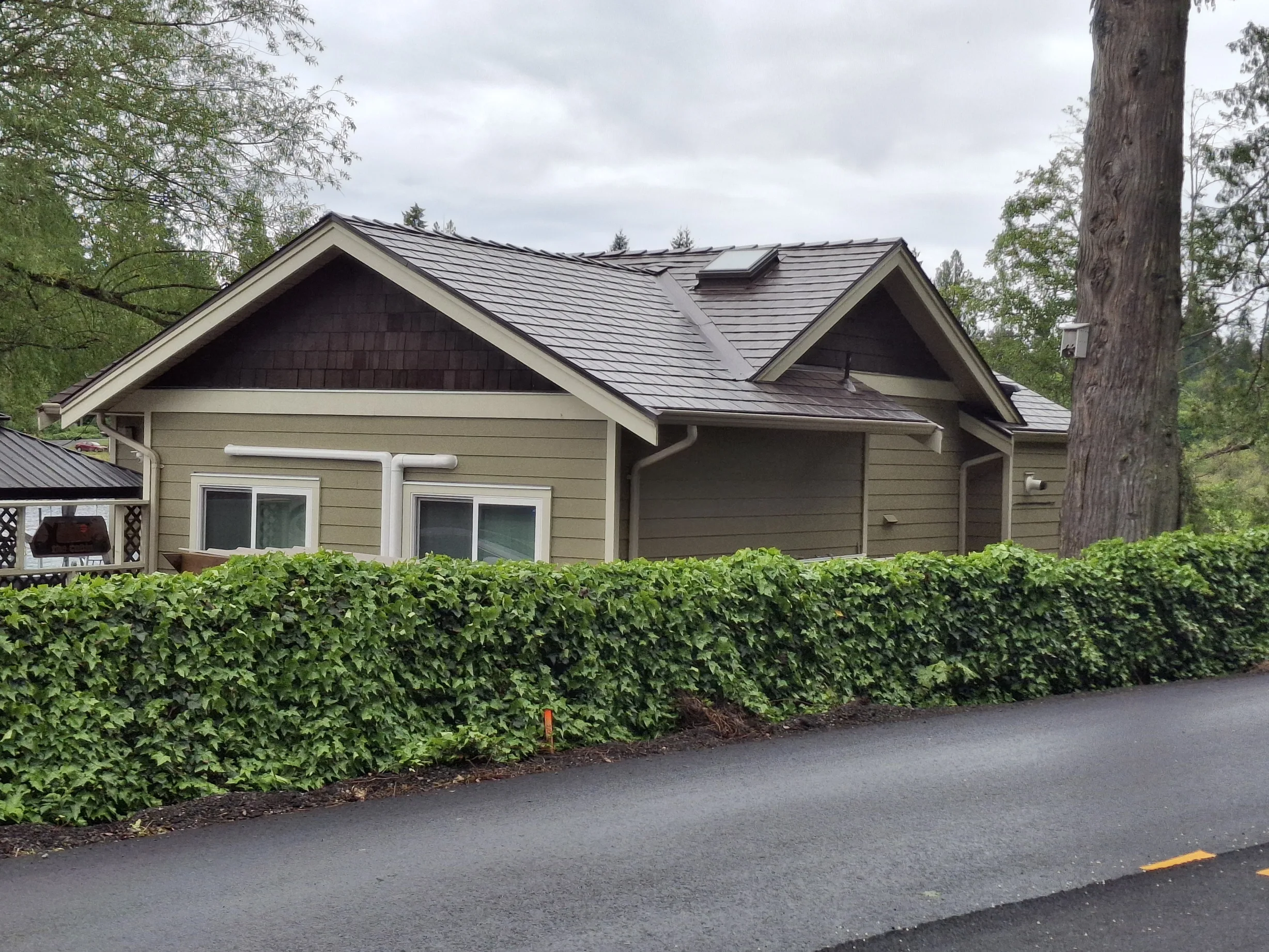 Colonial Brown Interlock Slate aluminum roof on a brown colonial home among trees, Shawnigan Lake, British Columbia