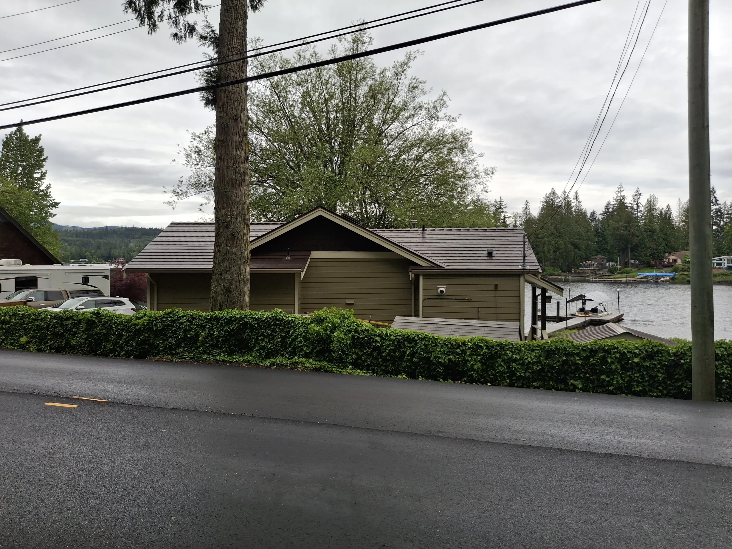 Colonial Brown Interlock Slate aluminum roof on a colonial home with a brown roof among tall trees and water, Shawnigan Lake, British Columbia