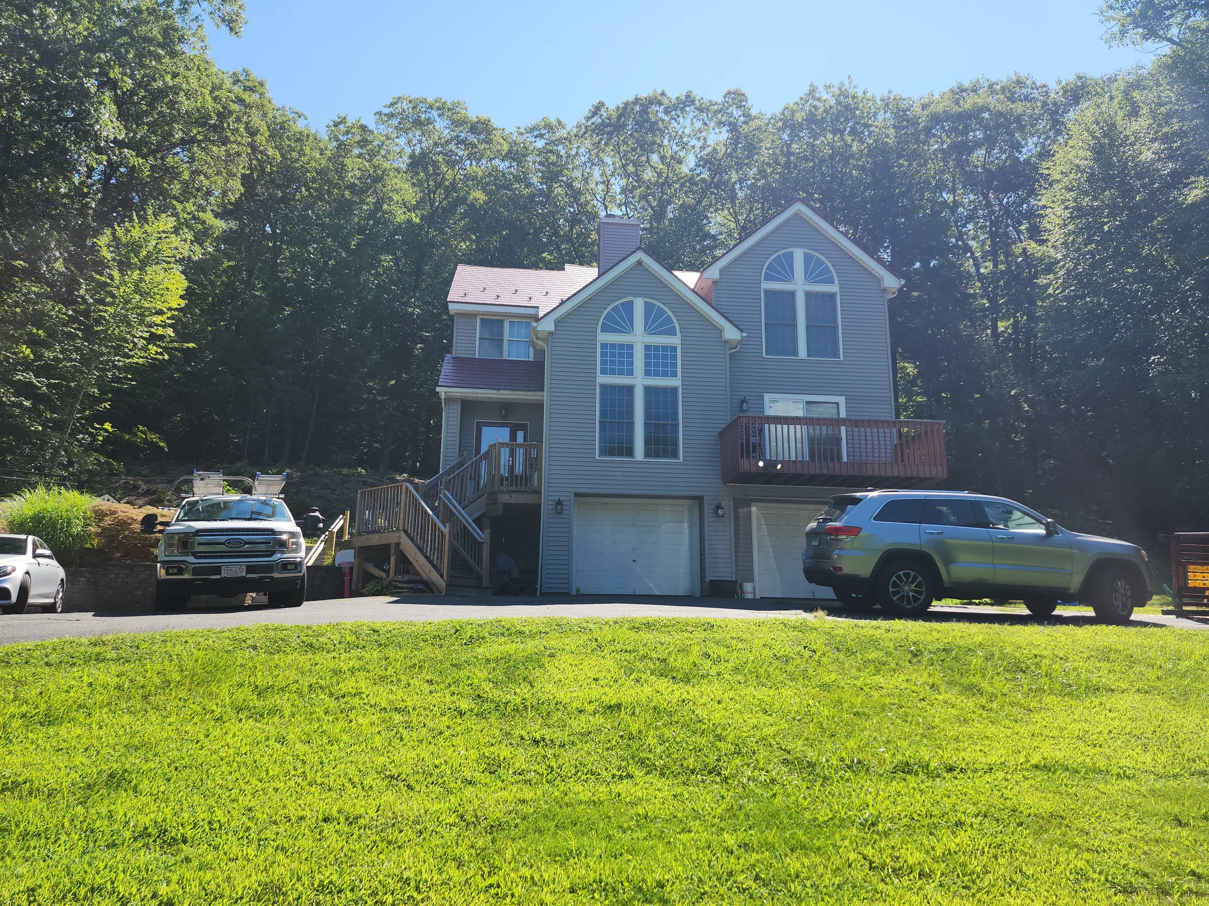 Tile Red Interlock Slate aluminum roof on a grey two-storey home with dormers among tall trees, Granby, Connecticut