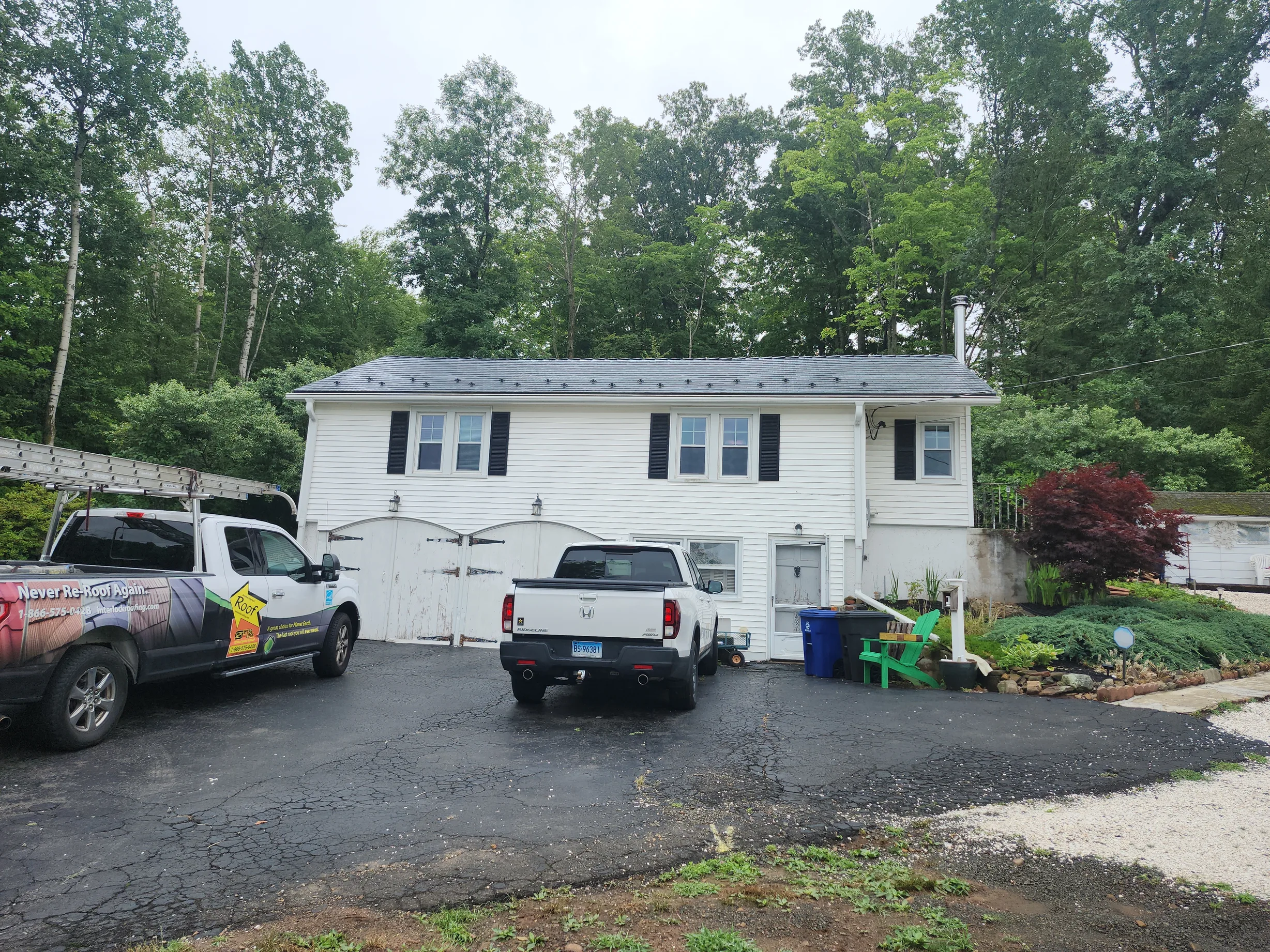 Deep Charcoal Interlock Cedar Shingle aluminum roof on a white two-storey home with a metal roof in a wooded area, East Haven, Connecticut