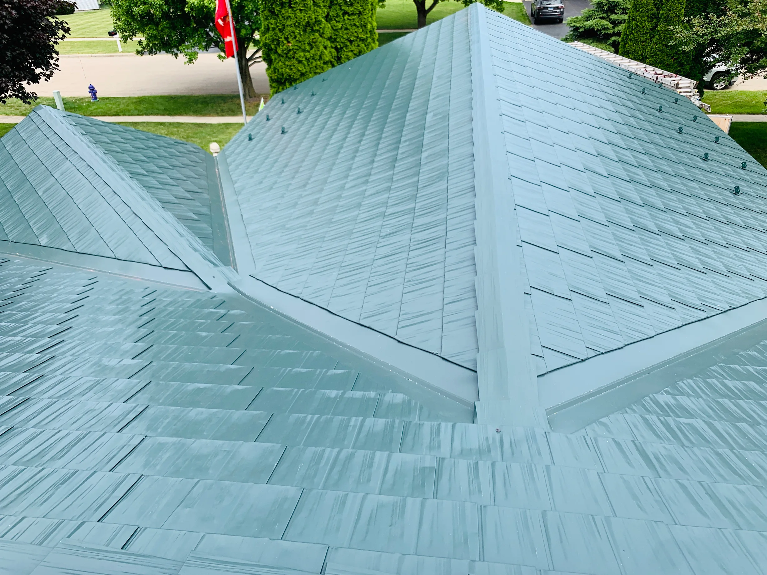 Hunter Green Interlock Shingle aluminum roof on a green metal roof on a two-storey home among tall pines in, Winnebago, Illinois