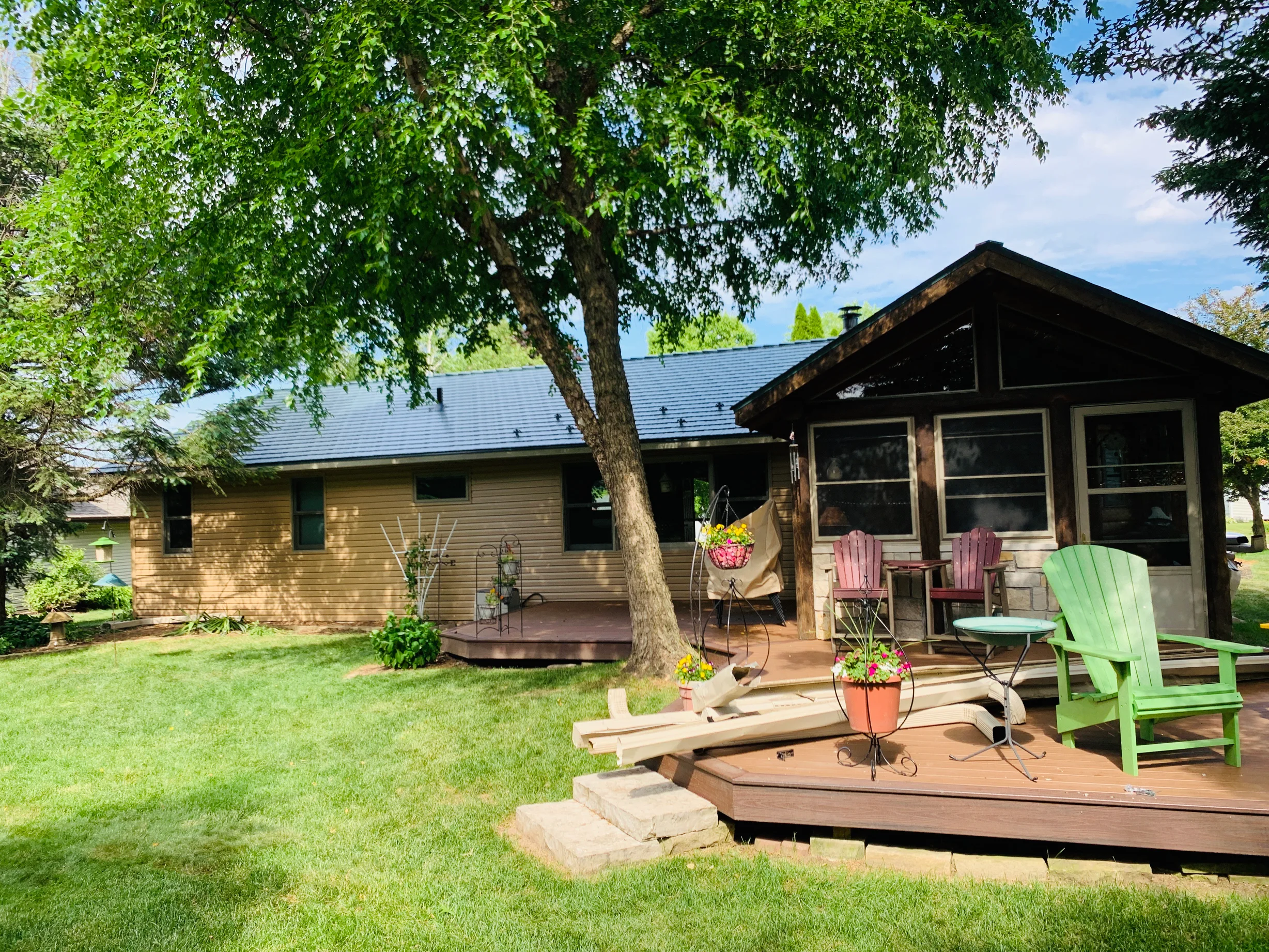 Hunter Green Interlock Shingle aluminum roof on a tan single-story home with a brown roof and a large tree, Winnebago, Illinois
