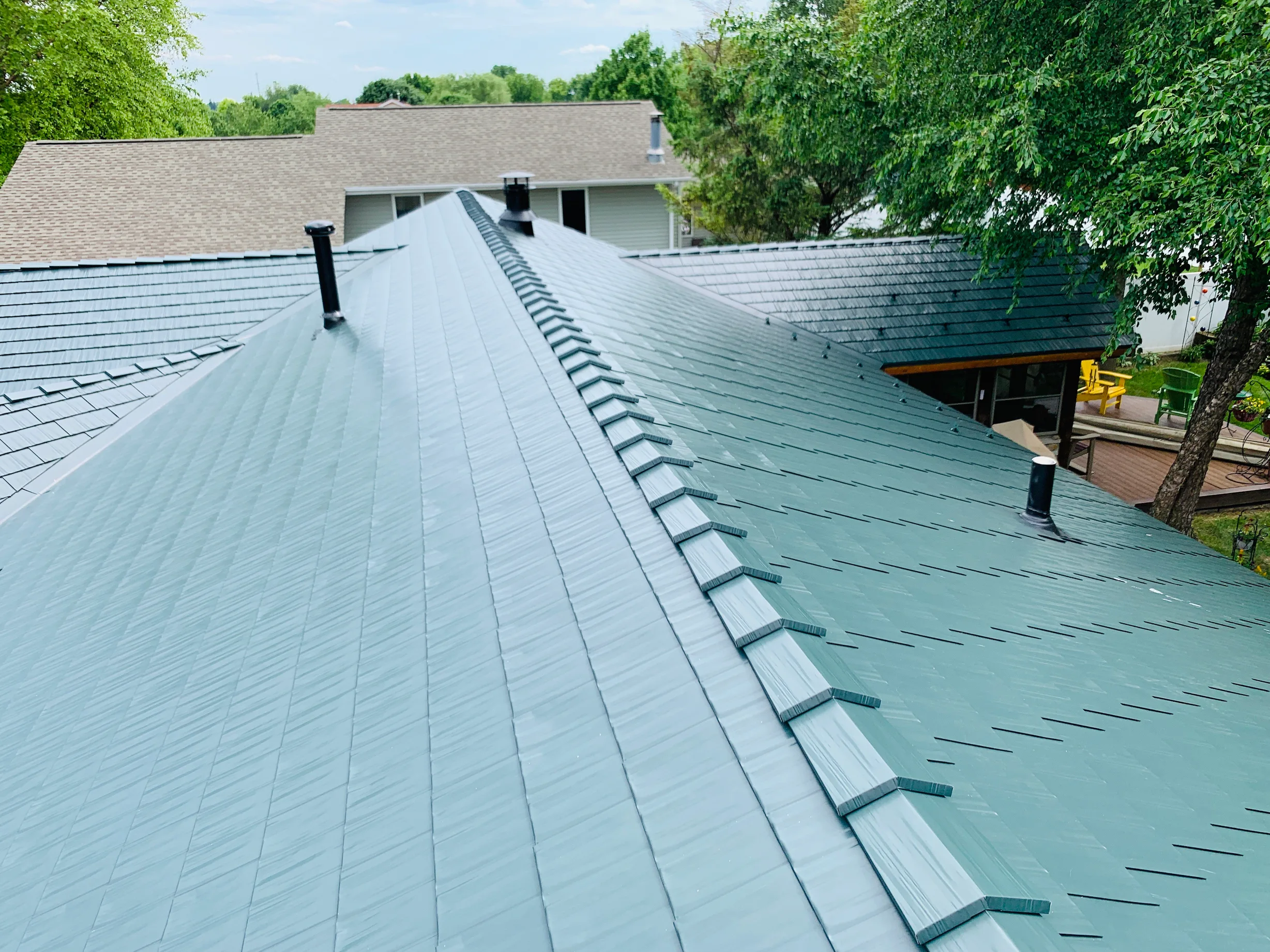 Hunter Green Interlock Shingle aluminum roof on a two-storey home with hunter green metal roof in a forest, Winnebago, Illinois