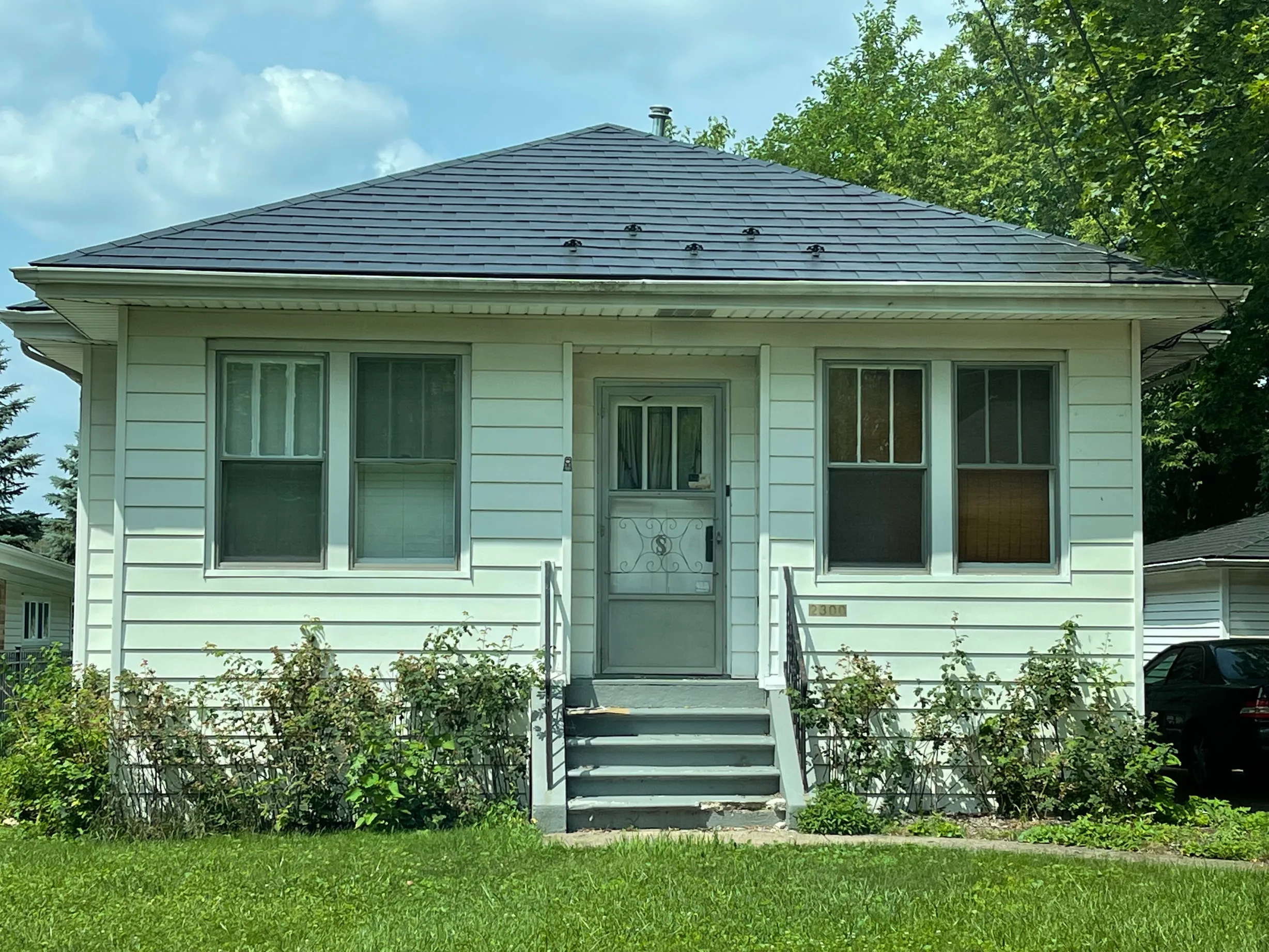Black Interlock Slate aluminum roof on a white one-storey ranch with a grey metal roof in a, Park Ridge, Illinois