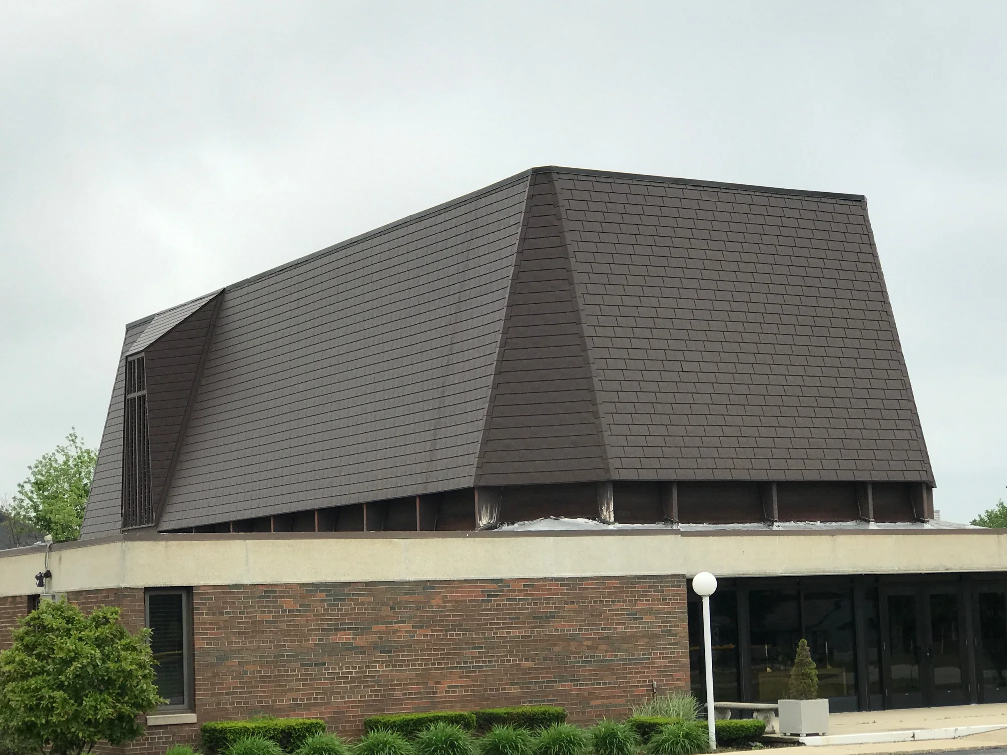 White Interlock IB Membrane aluminum roof on a suburban home with a brown metal roof among tall trees, Chicago Heights, Illinois