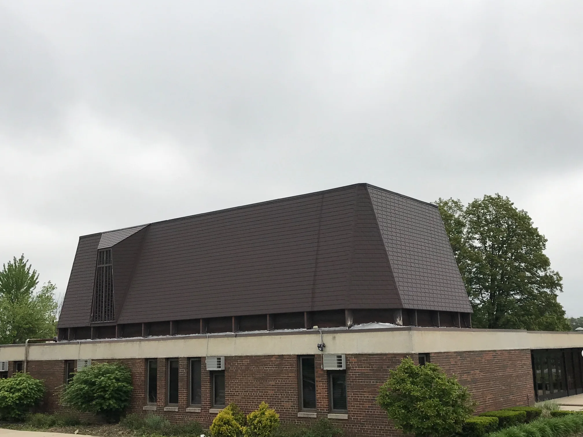 White Interlock IB Membrane aluminum roof on a brown single-storey home with dormers and shrubs in a, Chicago Heights, Illinois