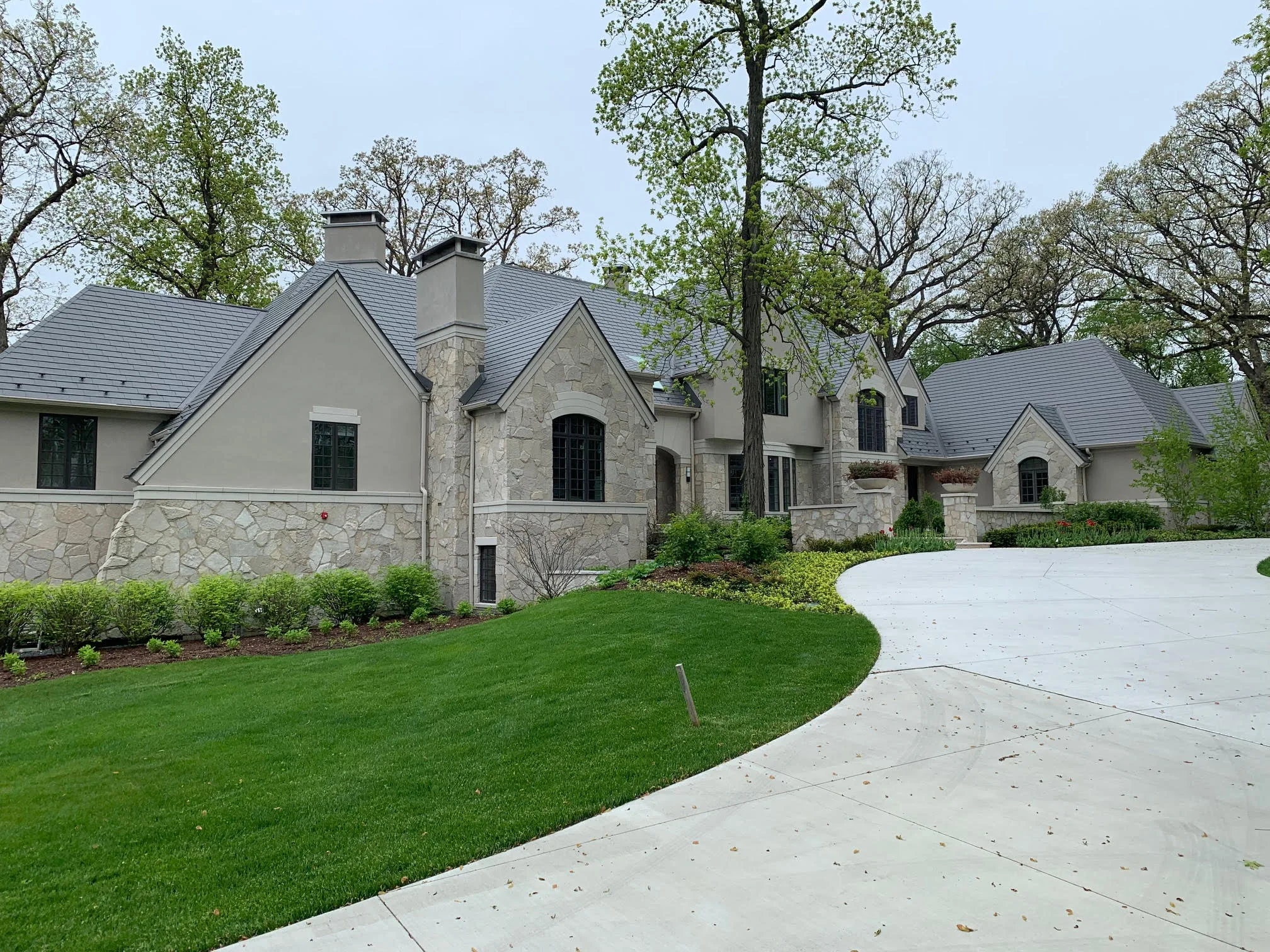 Musket Grey Interlock Slate aluminum roof on a grey two-storey colonial home with dormers in a forested, Long Grove, Illinois