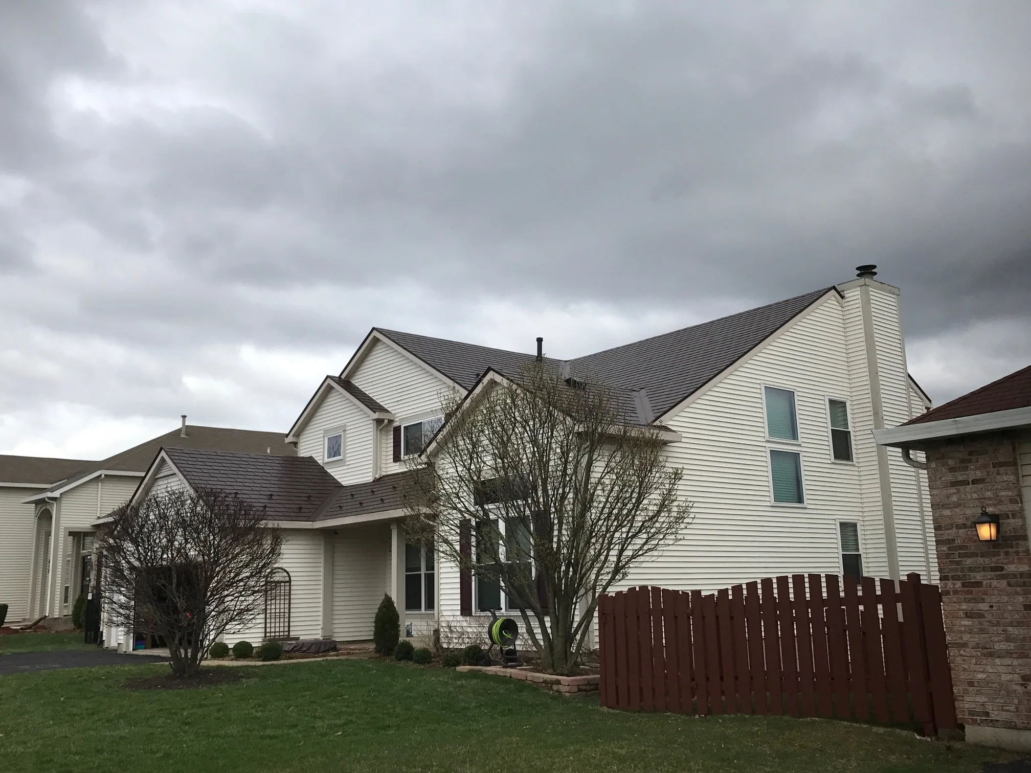 Colonial Brown Interlock Slate aluminum roof on a white Colonial home with dormers and a brown fence, Carol Stream, Illinois