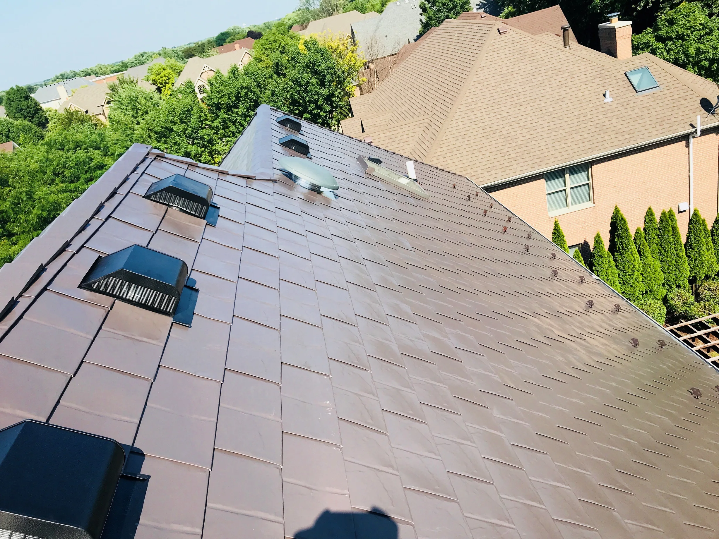 Tudor Brown Interlock Slate aluminum roof on a brown house with a metal roof among tall trees, Roselle, Illinois