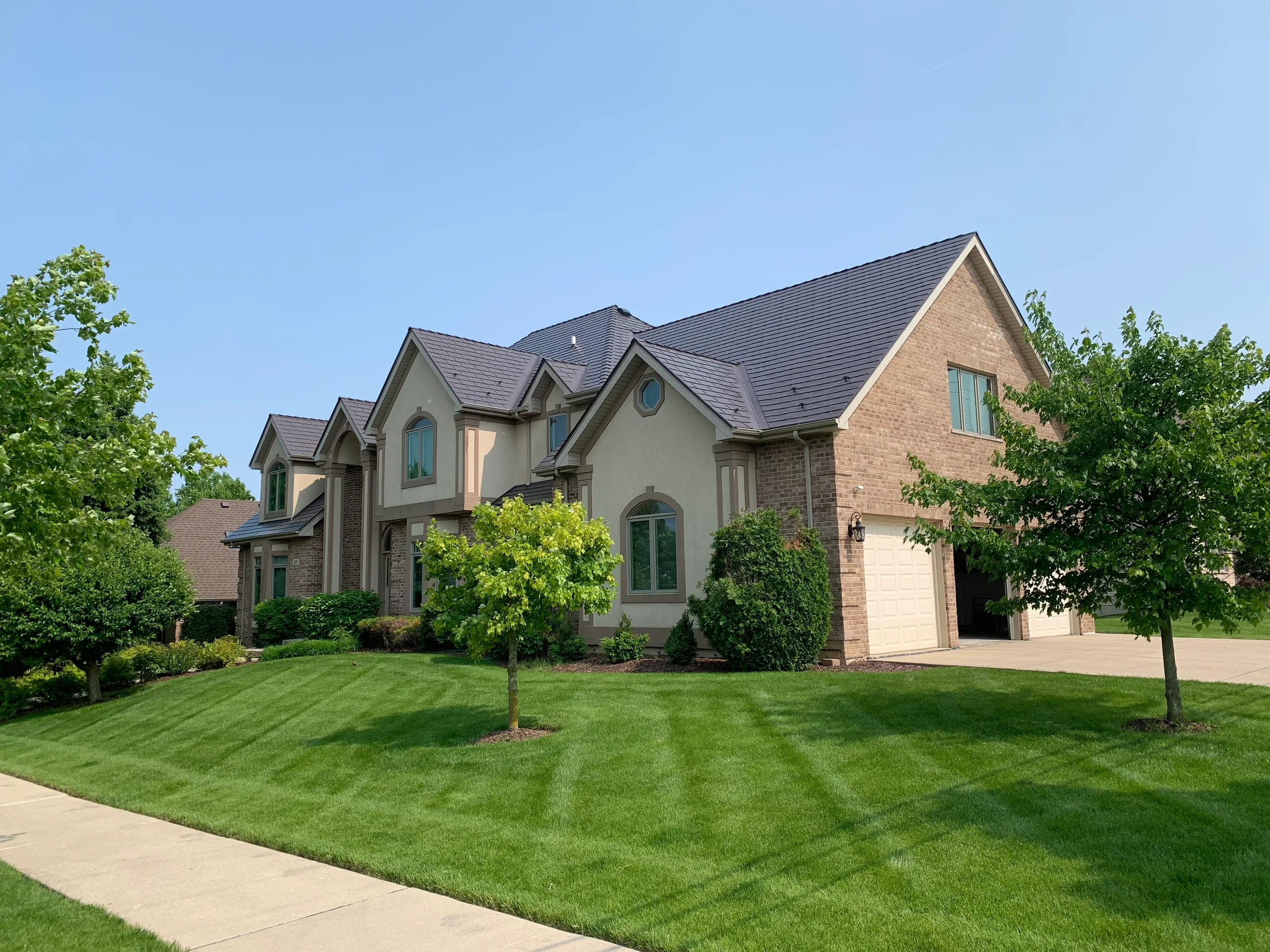 Tudor Brown Interlock Slate aluminum roof on a Tudor brown single-family home with dormers in a lush, Roselle, Illinois