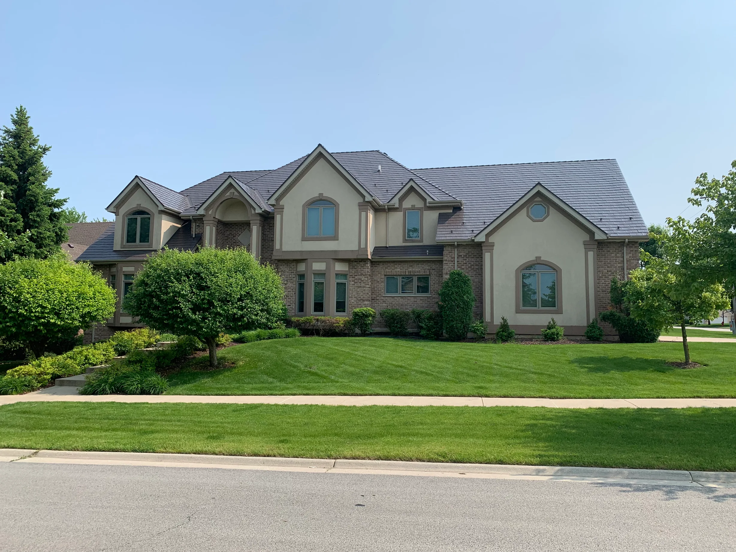 Tudor Brown Interlock Slate aluminum roof on a Tudor home with brown brick and cream siding in a, Roselle, Illinois