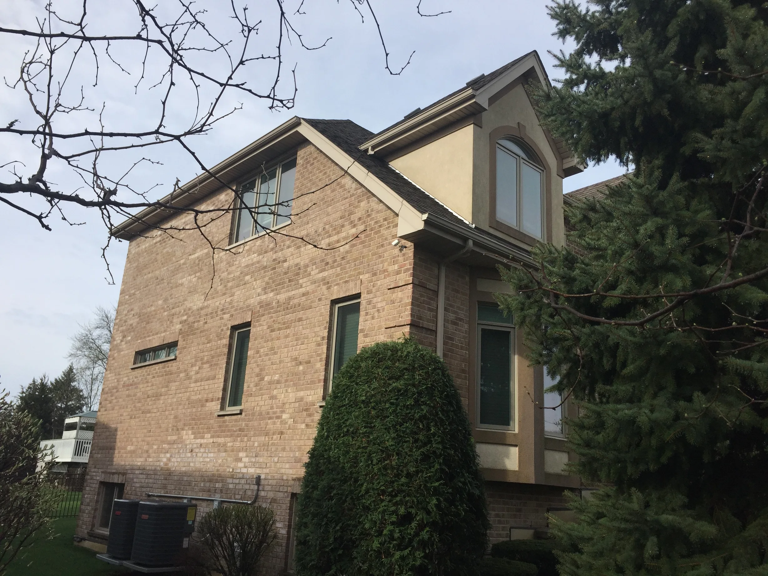 Tudor Brown Interlock Slate aluminum roof on a brown two-storey Tudor home among tall trees, Roselle, Illinois