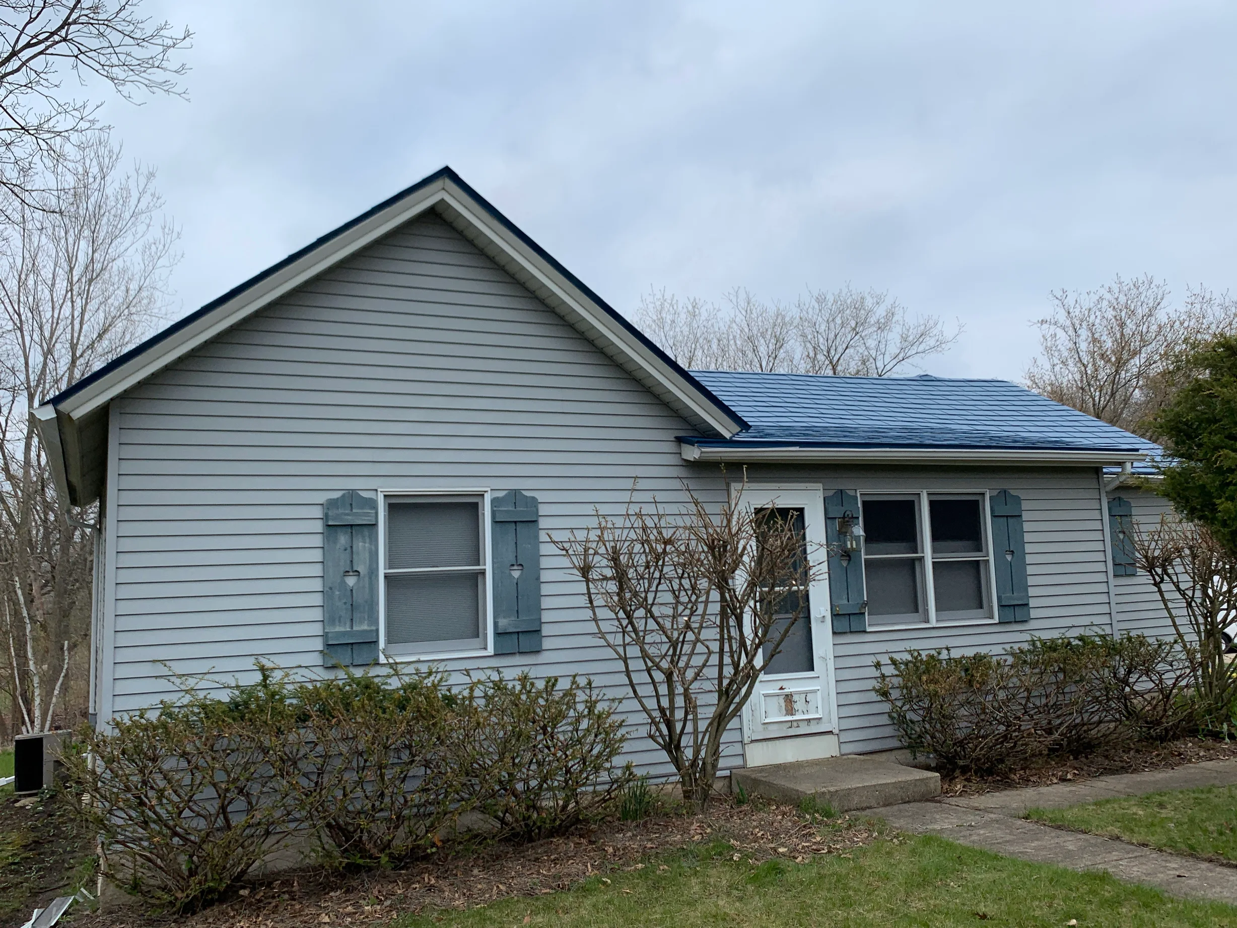 Royal Blue Interlock Slate aluminum roof on a two-storey home with a grey roof in a suburban setting, Woodstock, Illinois