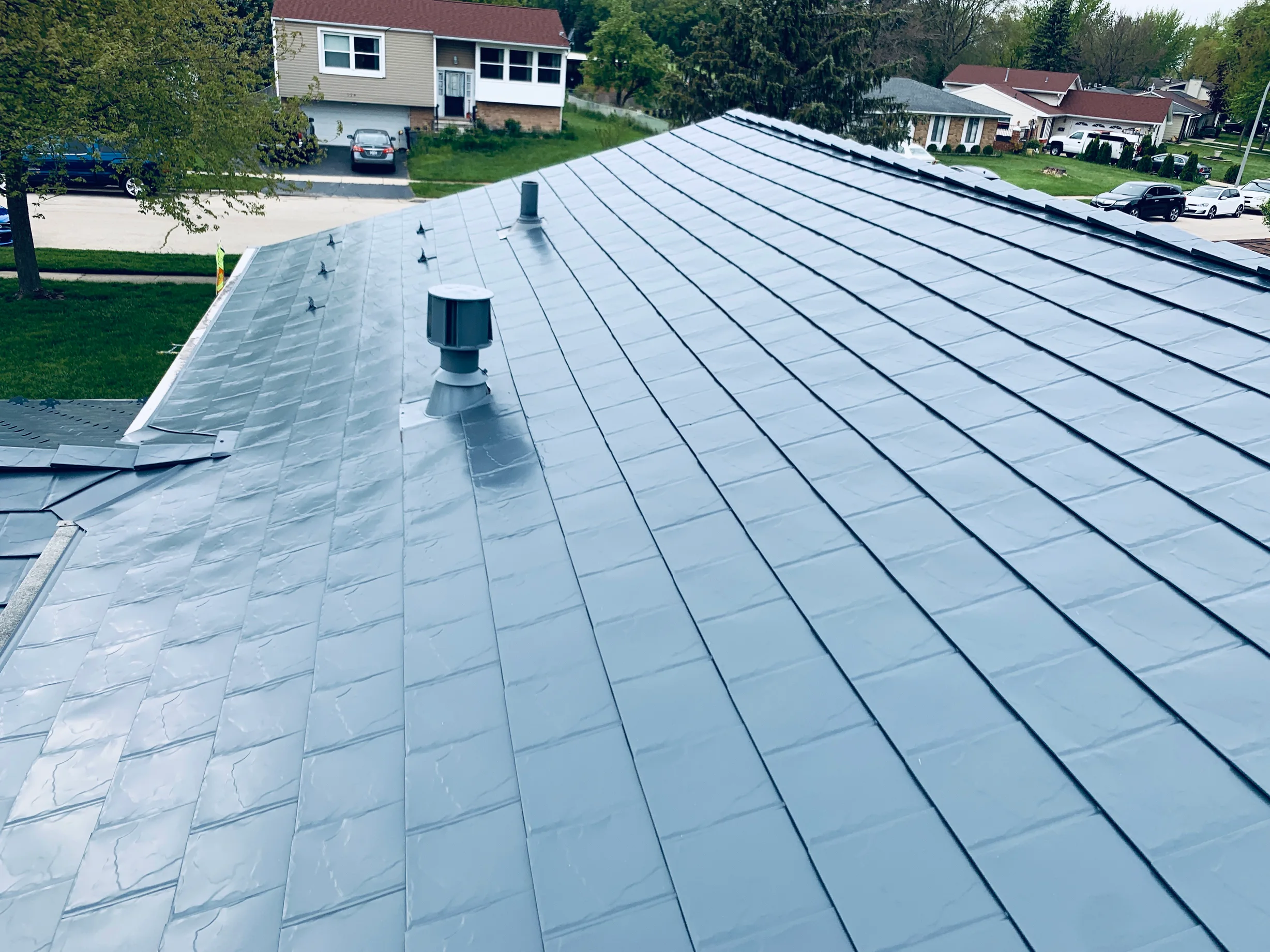 Deep Charcoal Interlock Slate aluminum roof on a tan two-storey home with a red roof and a metal roof in, Elgin, Illinois