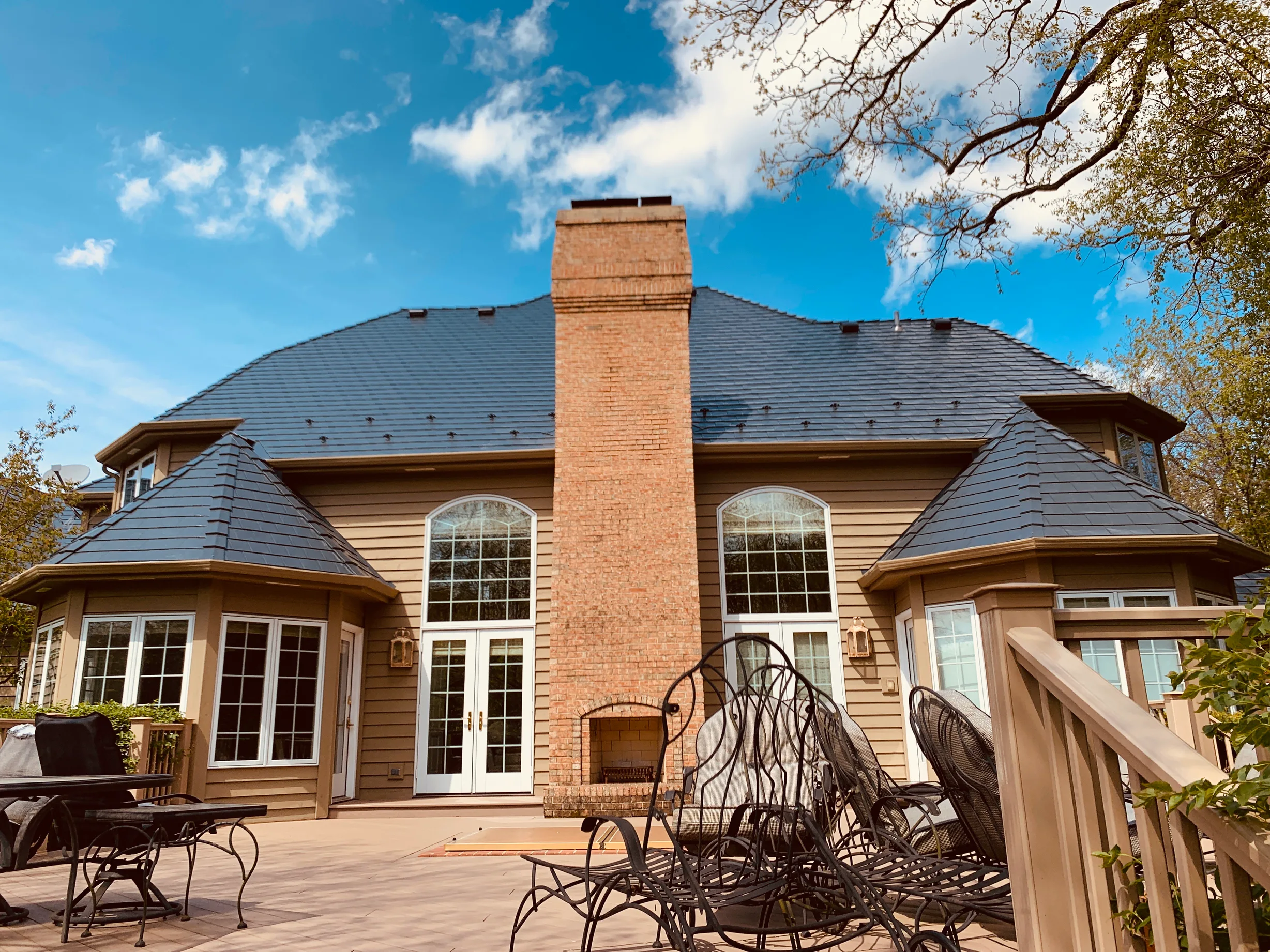 Deep Charcoal Interlock Slate aluminum roof on a tan colonial home with a brown metal roof and chimney, Crystal Lake, Illinois