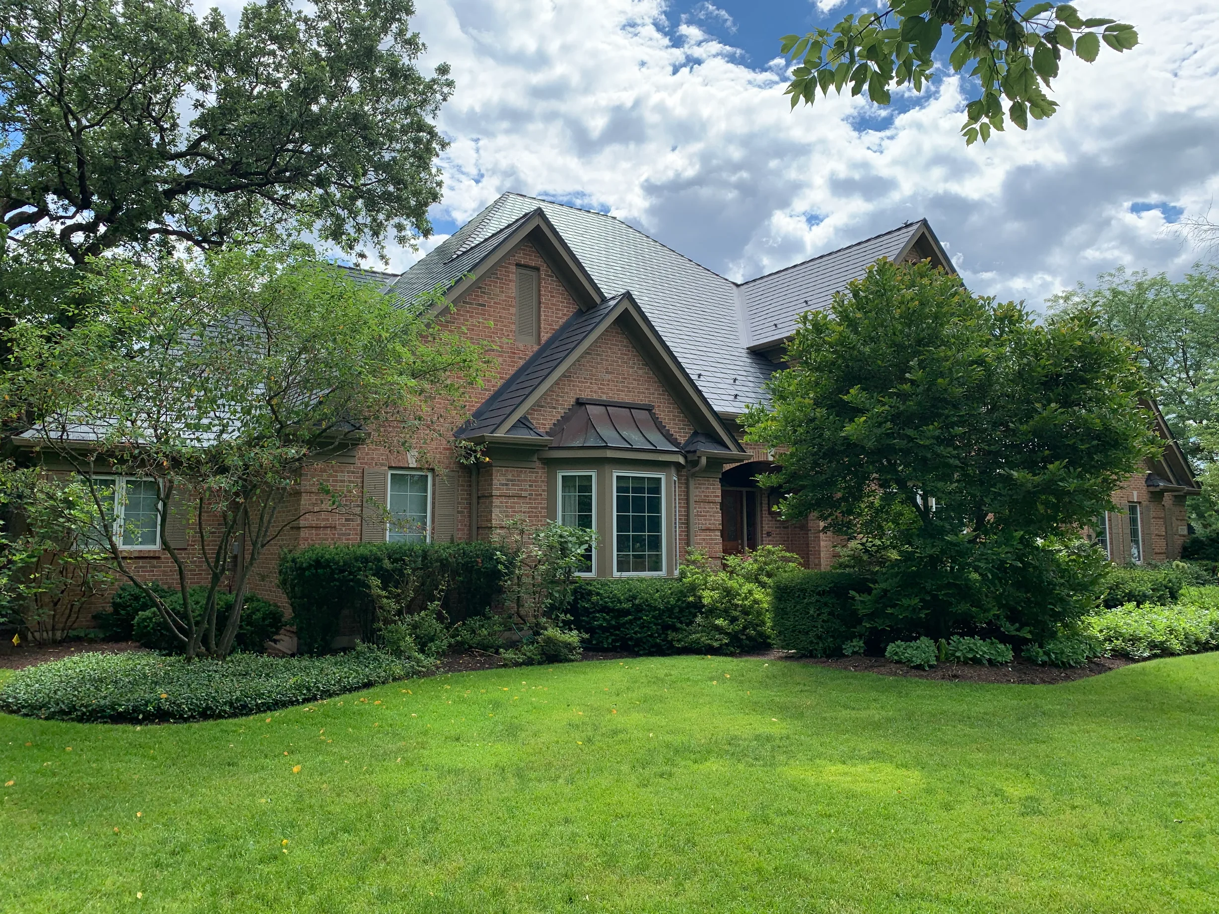 Deep Charcoal Interlock Slate aluminum roof on a red brick home with a metal roof and two gables in a, Crystal Lake, Illinois