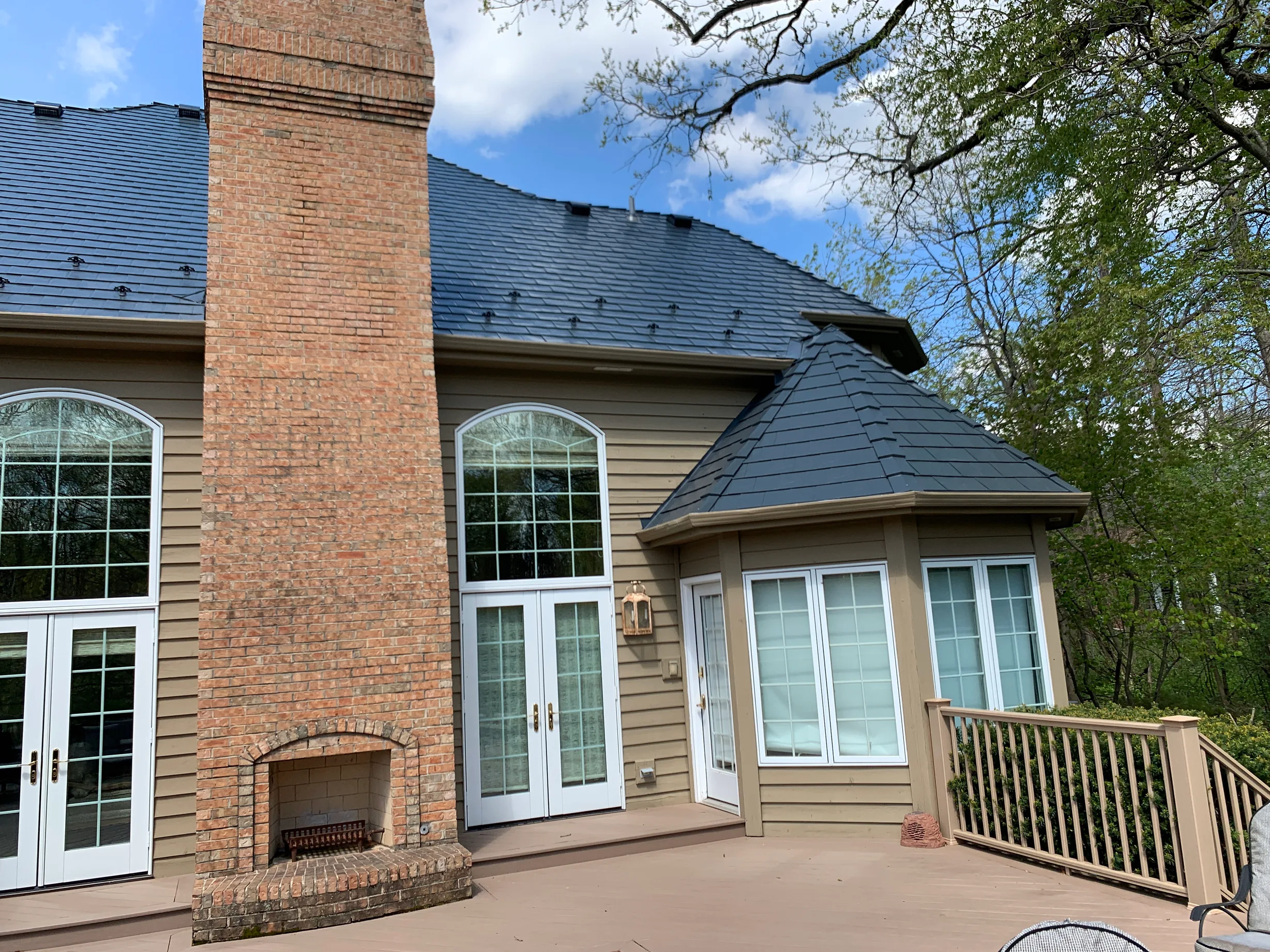 Deep Charcoal Interlock Slate aluminum roof on a tan Colonial home with a slate roof among trees and lake, Crystal Lake, Illinois