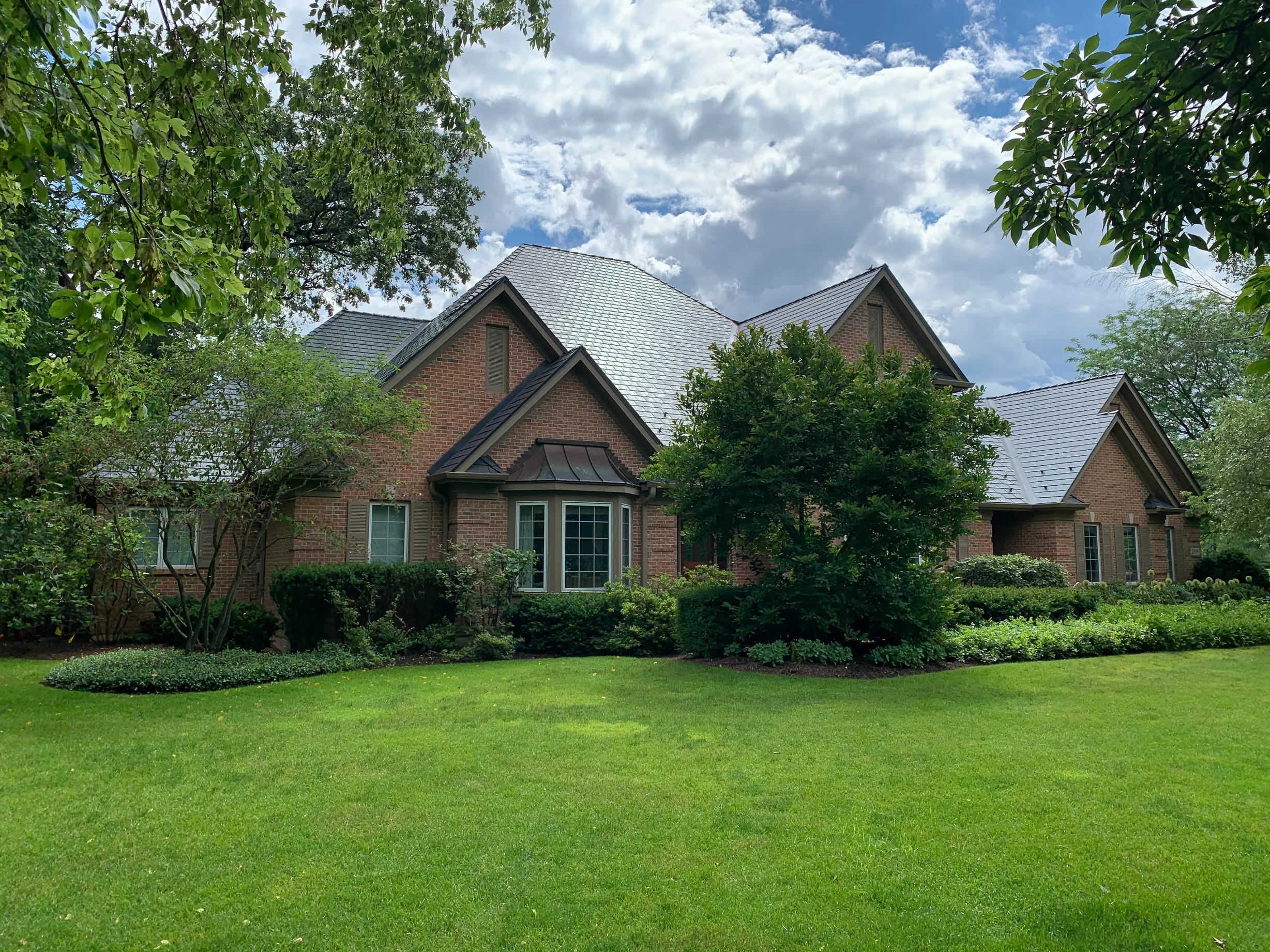 Deep Charcoal Interlock Slate aluminum roof being installed on a red brick house with a metal roof in a lakeside suburb, Crystal Lake, Illinois