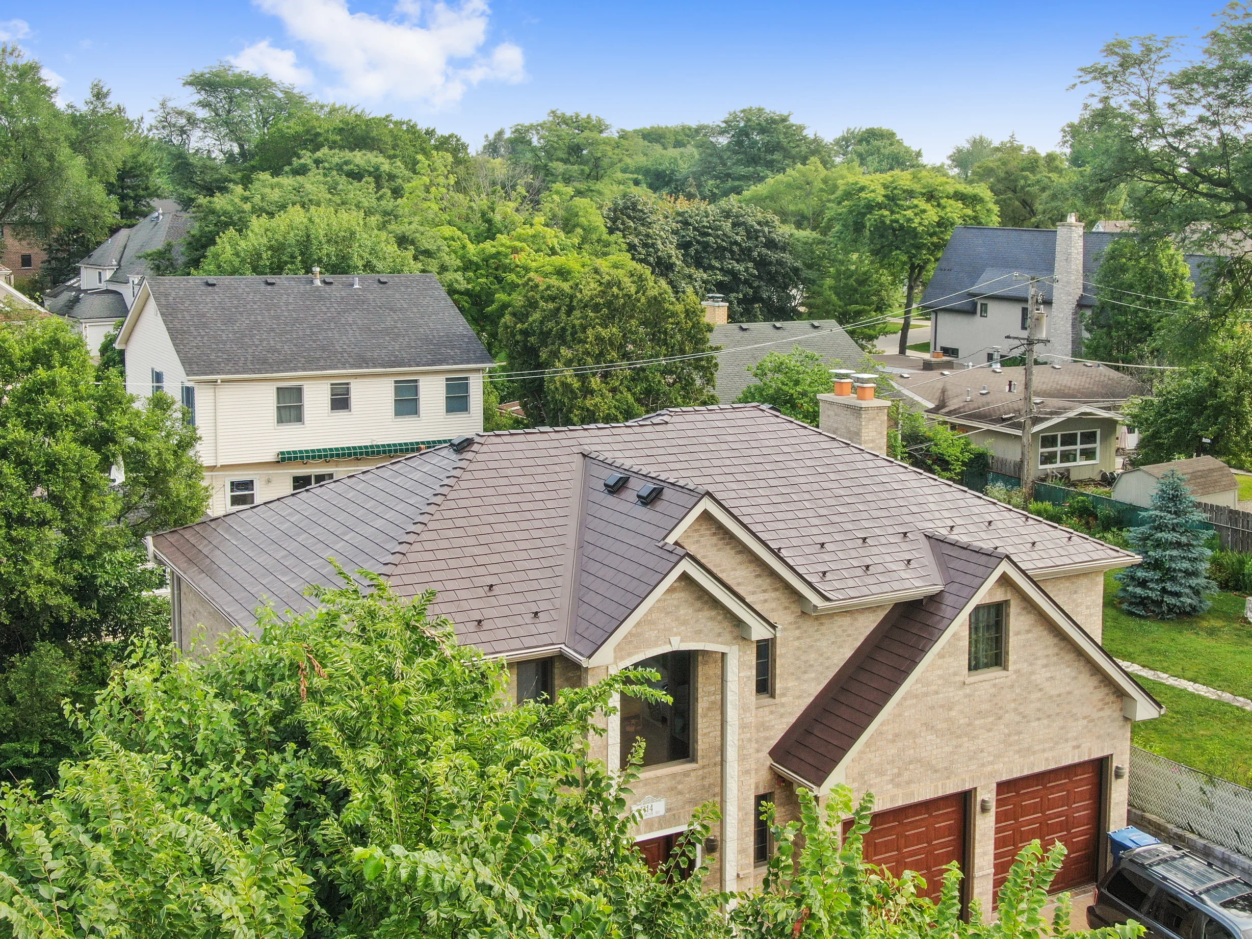 Colonial Brown Interlock Slate aluminum roof on a colonial style home with brown garage doors among trees, Calredon Hills, Illinois