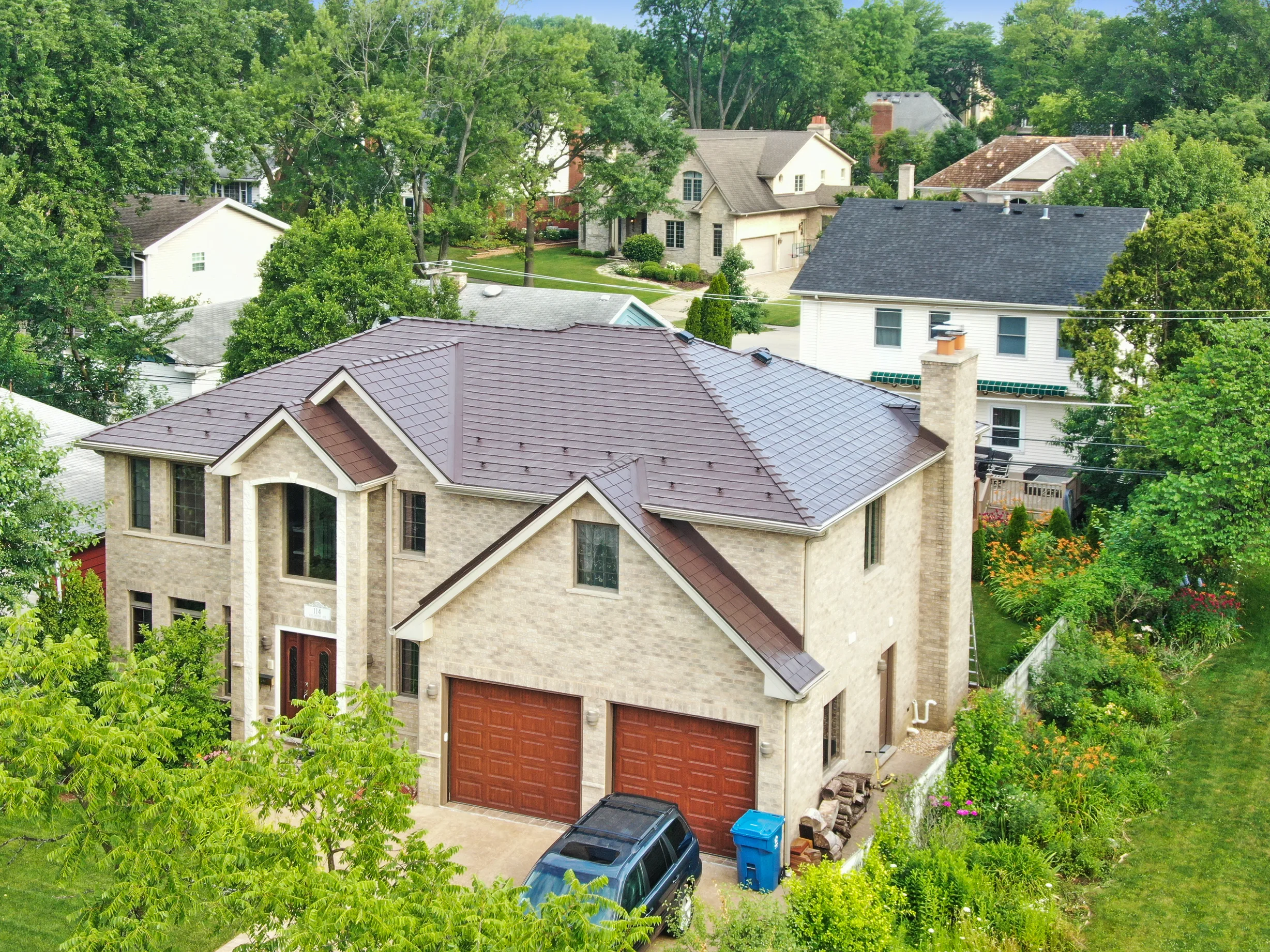 Colonial Brown Interlock Slate aluminum roof on a two-storey colonial home with dormers among lush greenery, Calredon Hills, Illinois